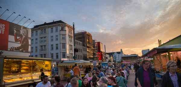 Menschen sitzen auf dem St. Pauli Nachtmarkt zwischen Ständen