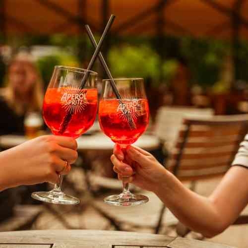 Zwei Gläser stoßen mit Aperol Spritz an.