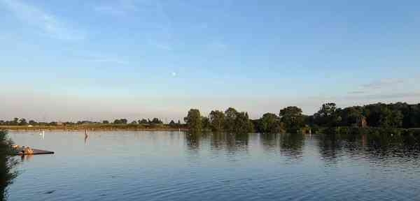 Der blaue Himmel und Bäume am Ufer spiegeln sich auf der Dove Elbe.