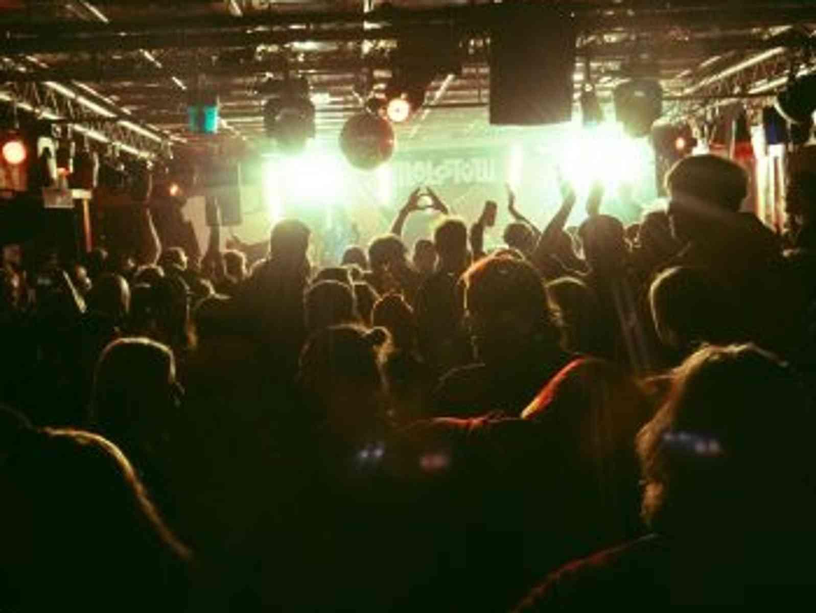 Personen feiern vor einer Bühne mit Partylicht.