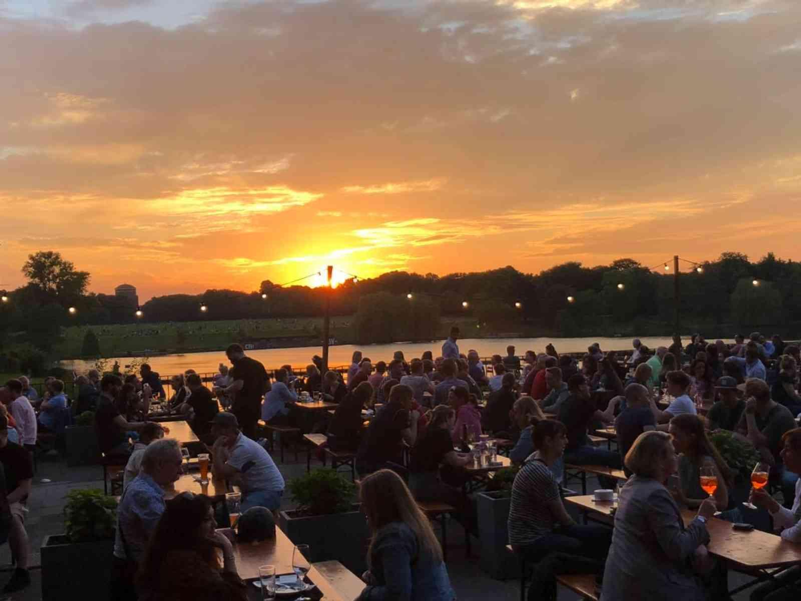 Viele Menschen sitzen bei Sonnenuntergang im Biergarten