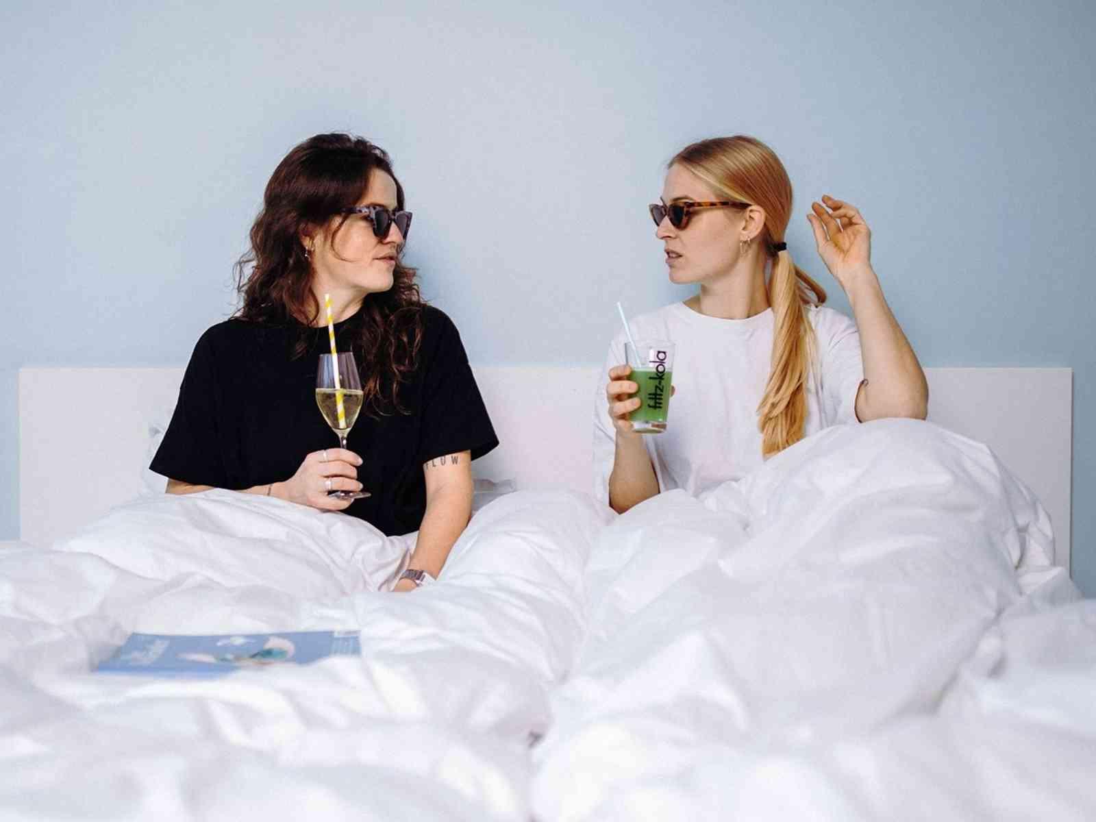 Zwei Personen mit Gläsern im Bett