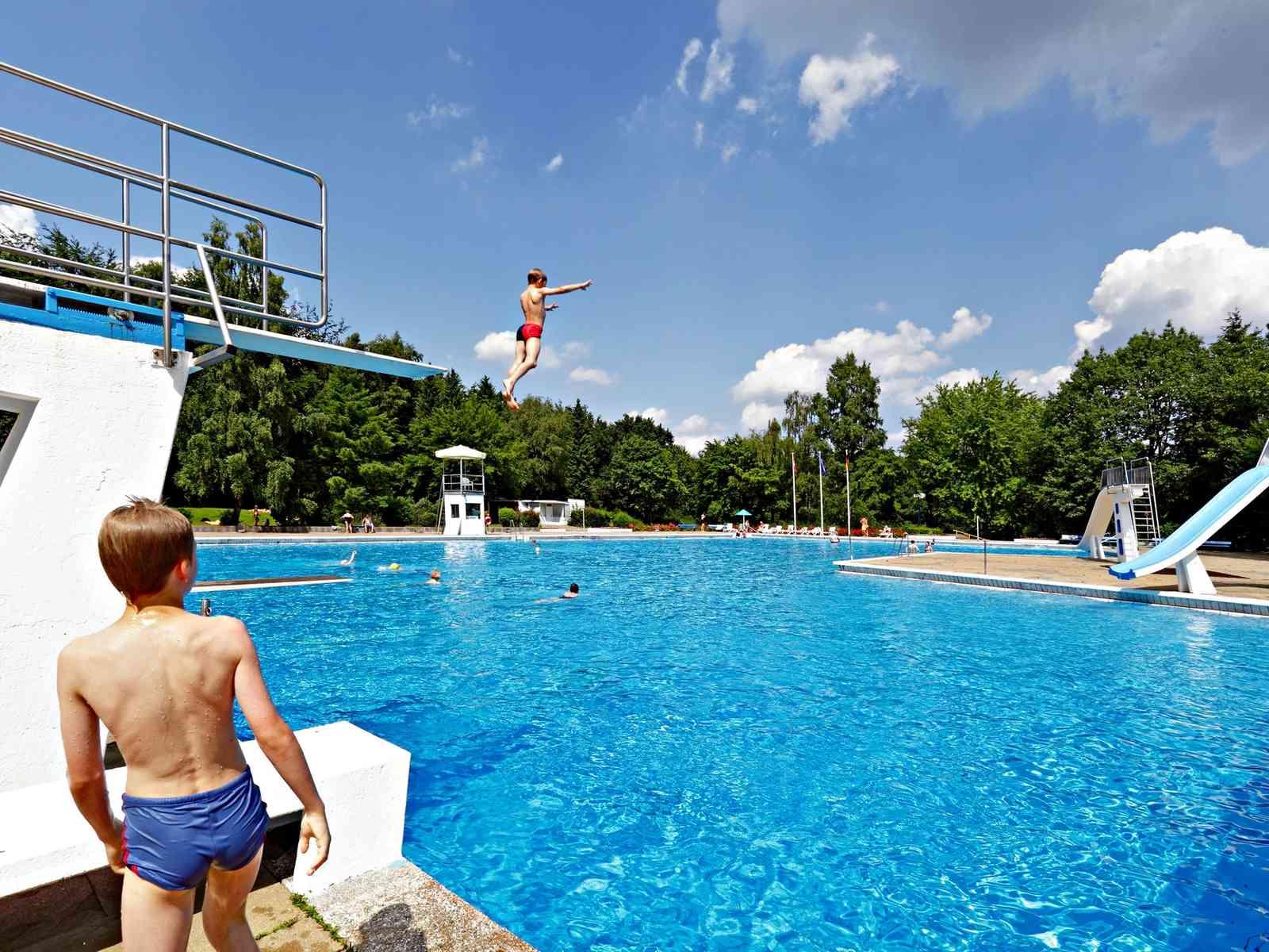 Kind spingt von 5 Meter Tum in Schwimmbecken