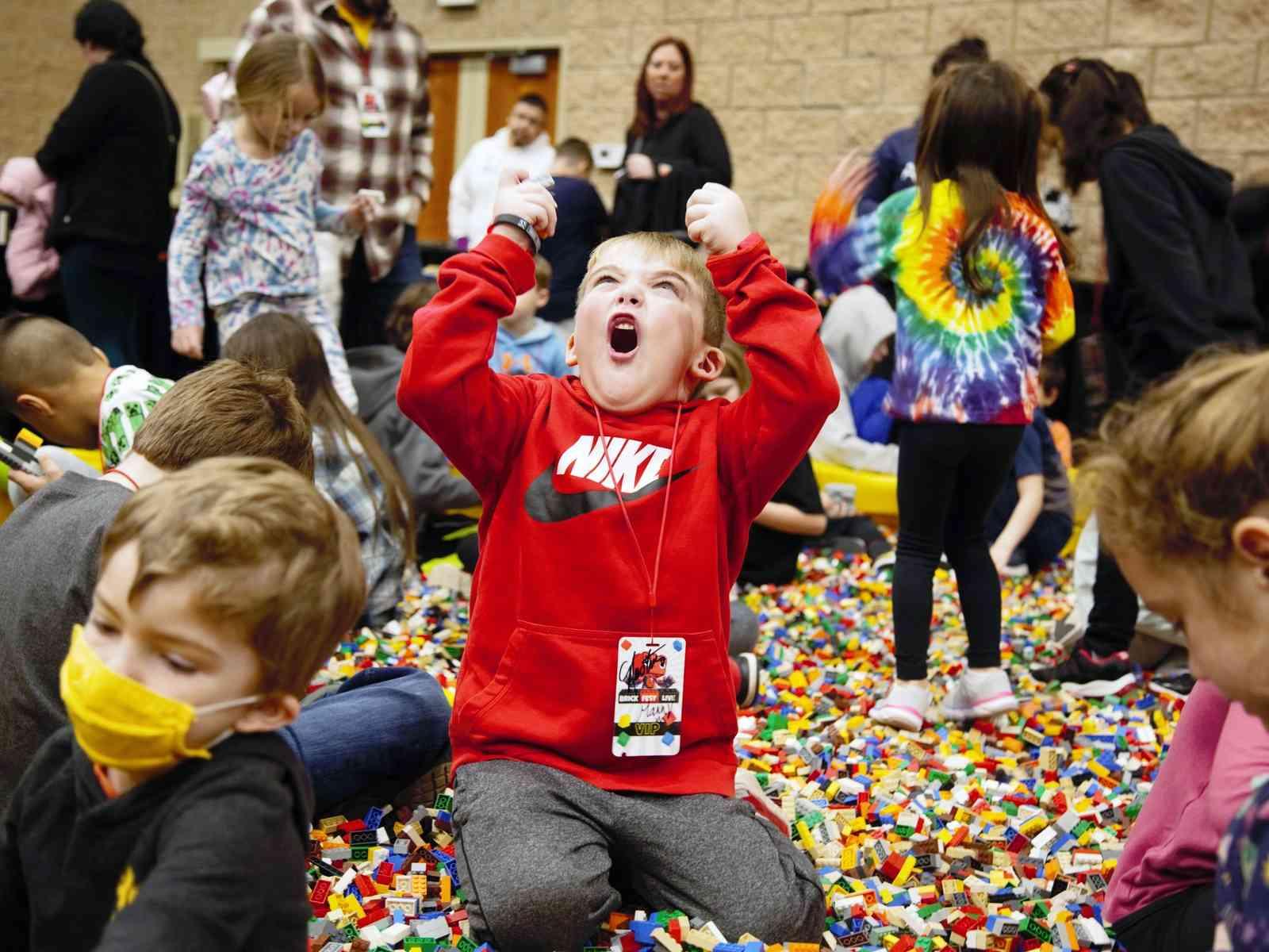 Kind freut sich, umgeben von Legosteinen