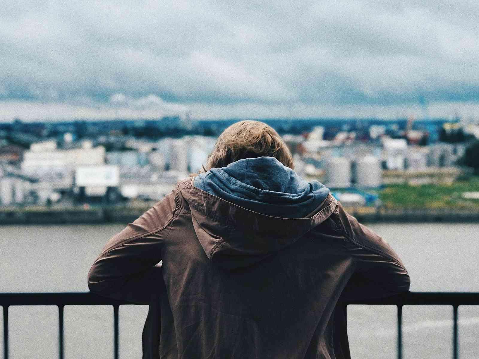 Rückenansicht einer Person, die von der Elbphilharmonie über den Hamburger Hafen blickt.