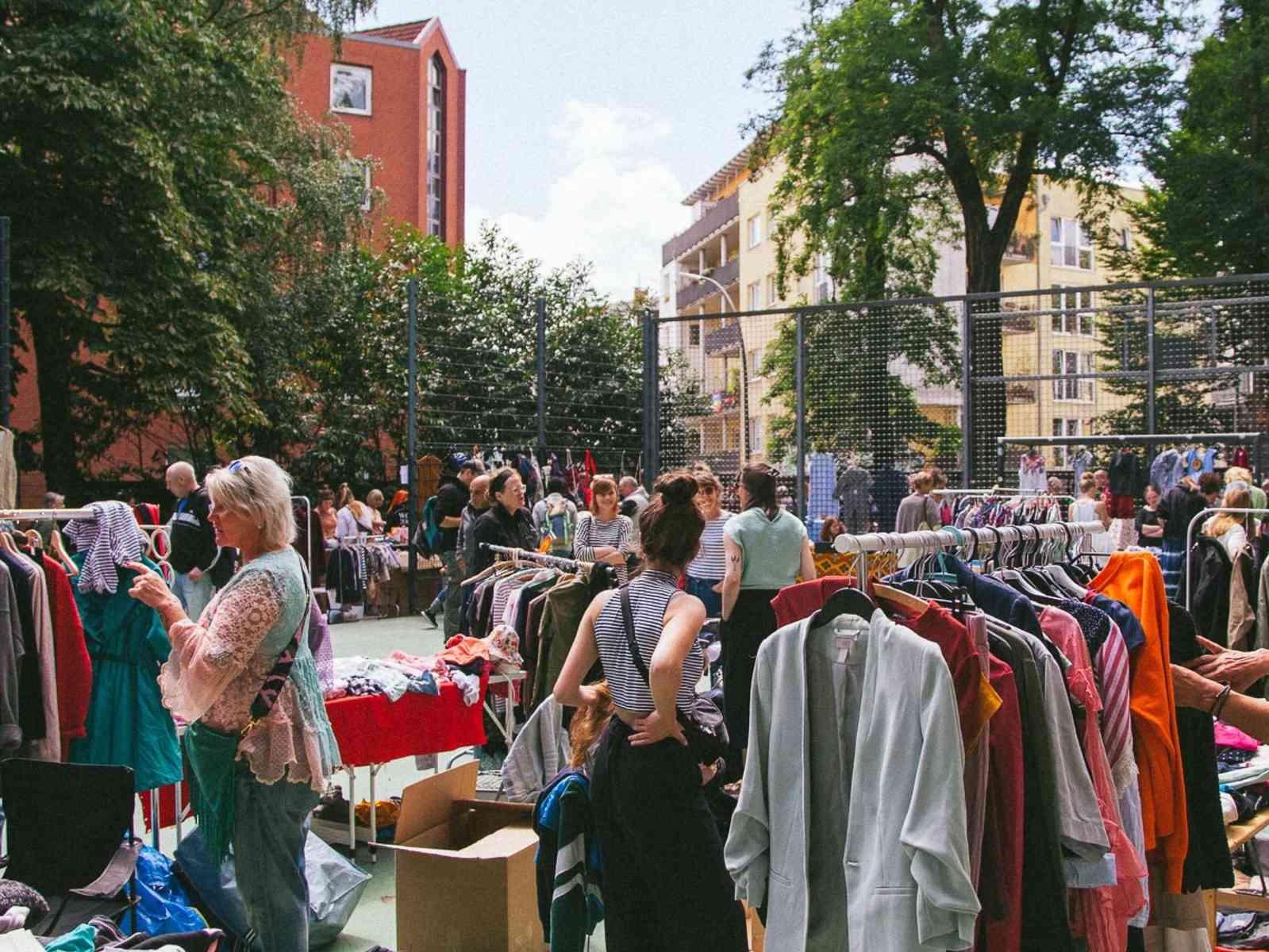 Personen bei Kleiderstangen auf einem Flohmarkt