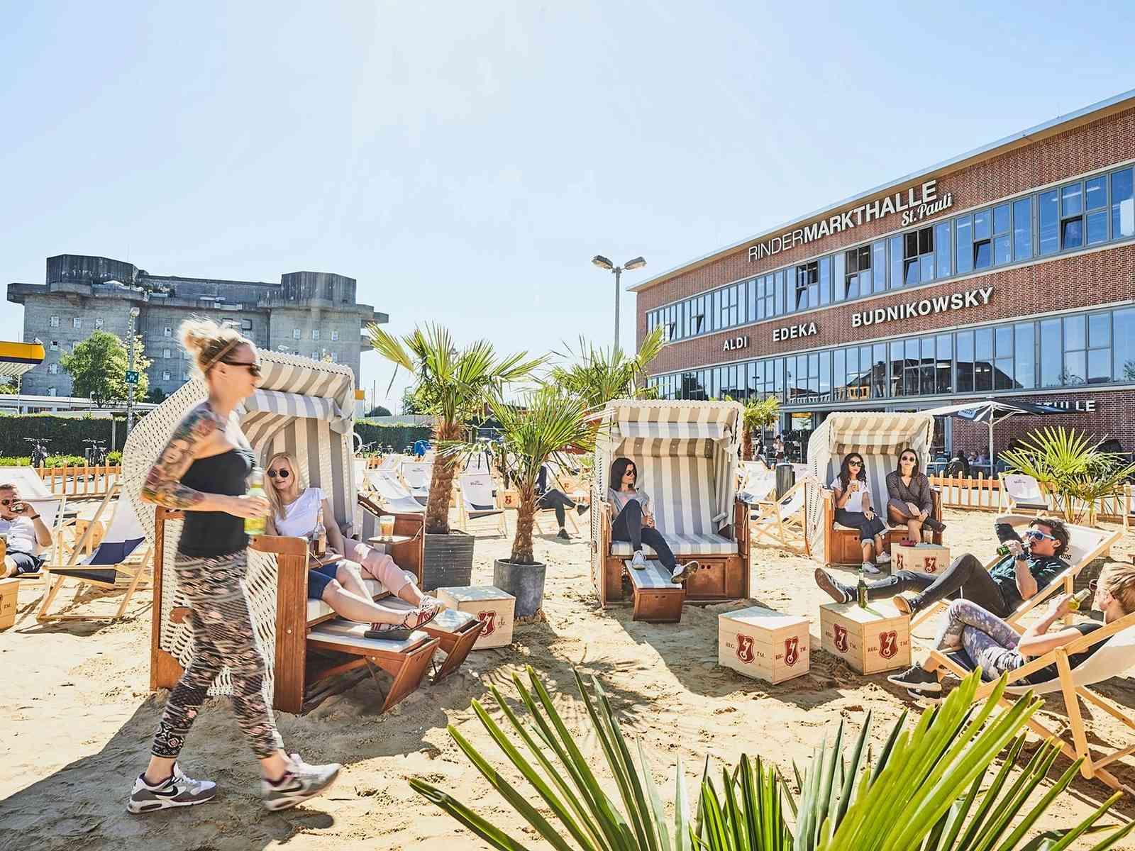 Personen sitzen in Strandkörben am Karo Beach vor der Rindermarkthalle.