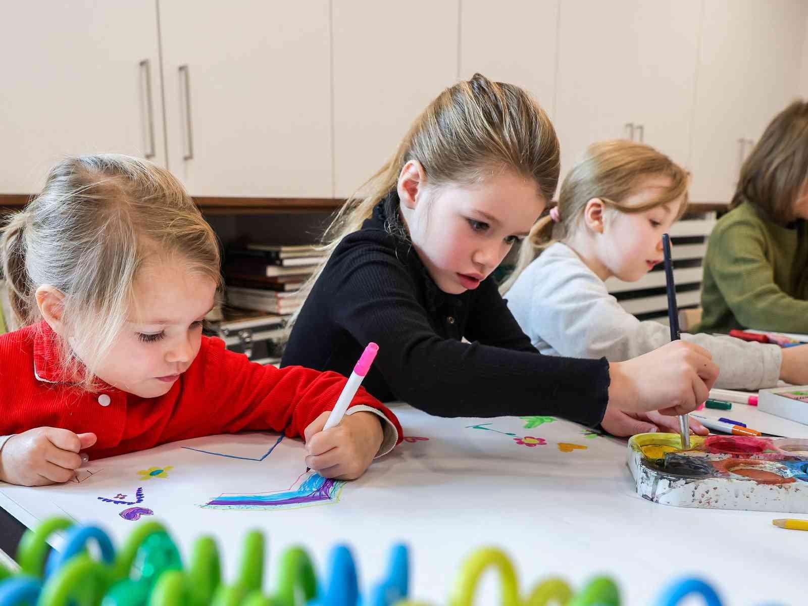 Kinder malen an einem Tisch