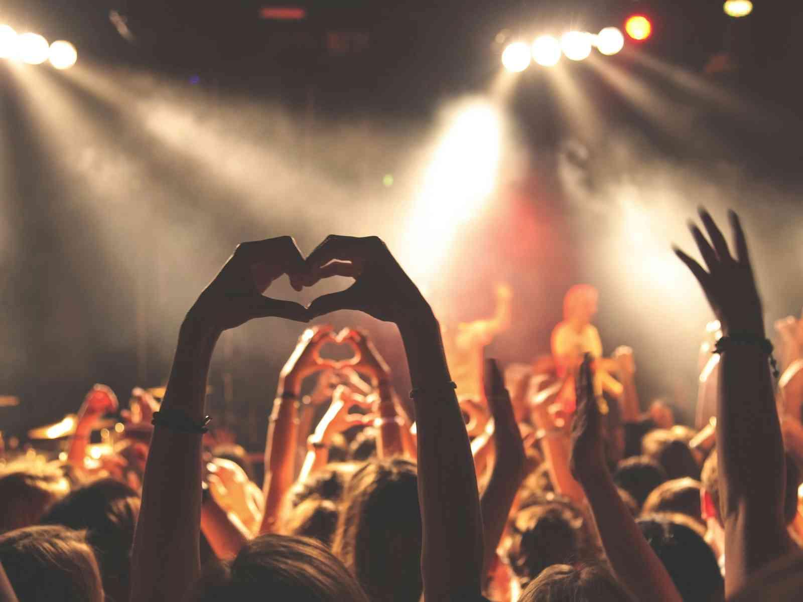 Eine Person zeigt ein Herz mit den Fingern auf einem Konzert