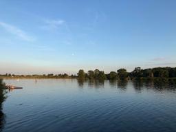 Der blaue Himmel und Bäume am Ufer spiegeln sich auf der Dove Elbe.