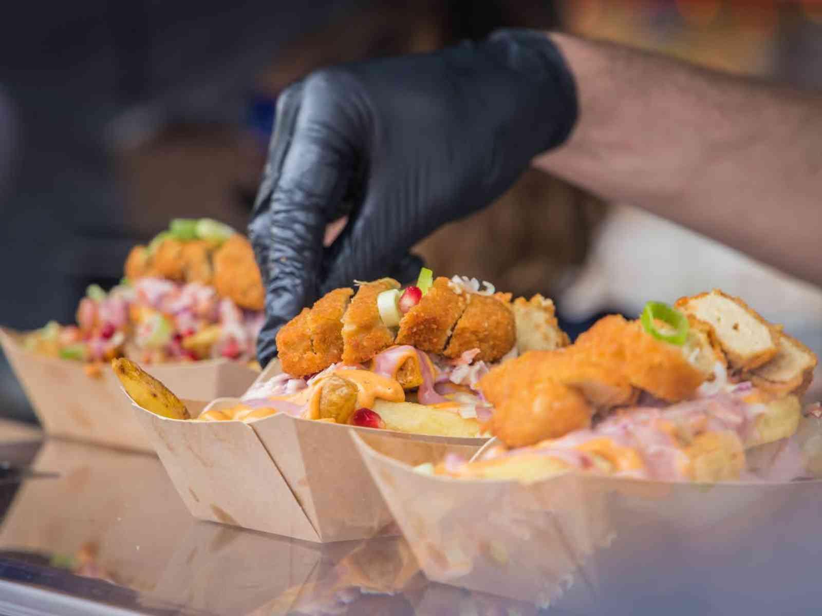 Hand mit Handschuh bereitet Essen zu.