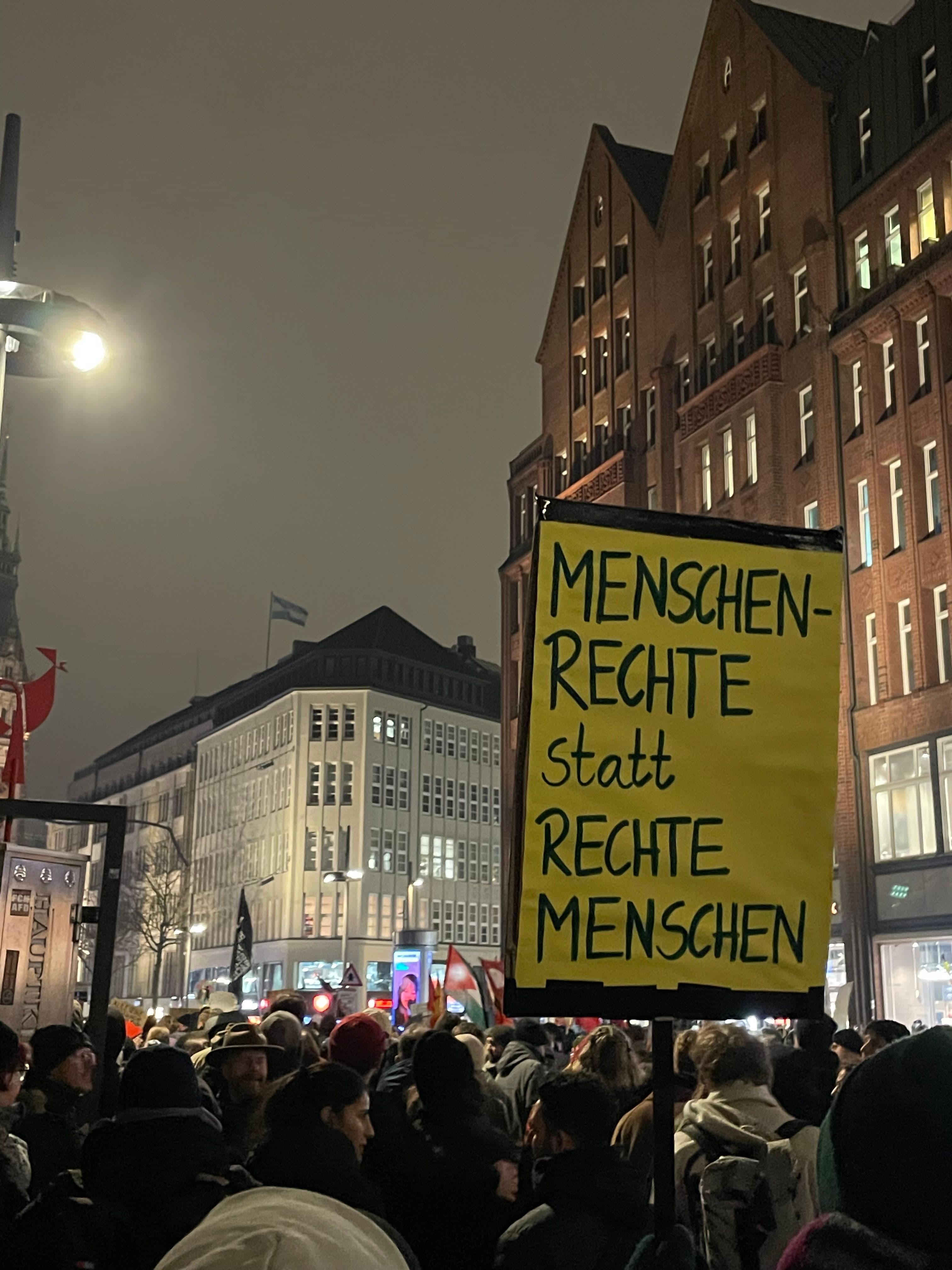 Ein Demoschild mit der Aufschrift "Menschenrecht statt rechte Menschen" wird hochgehalten