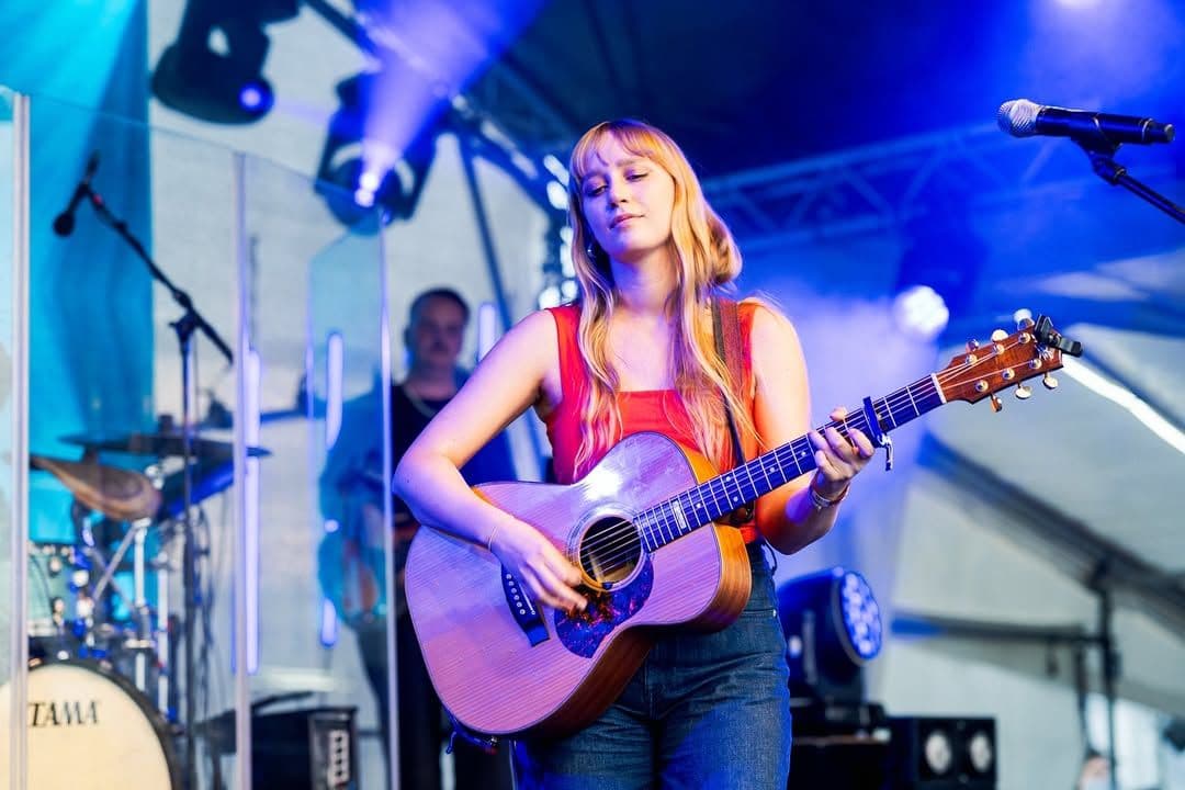 Die Musikerin VINTER steht mit einer Gitarre auf einer Bühne