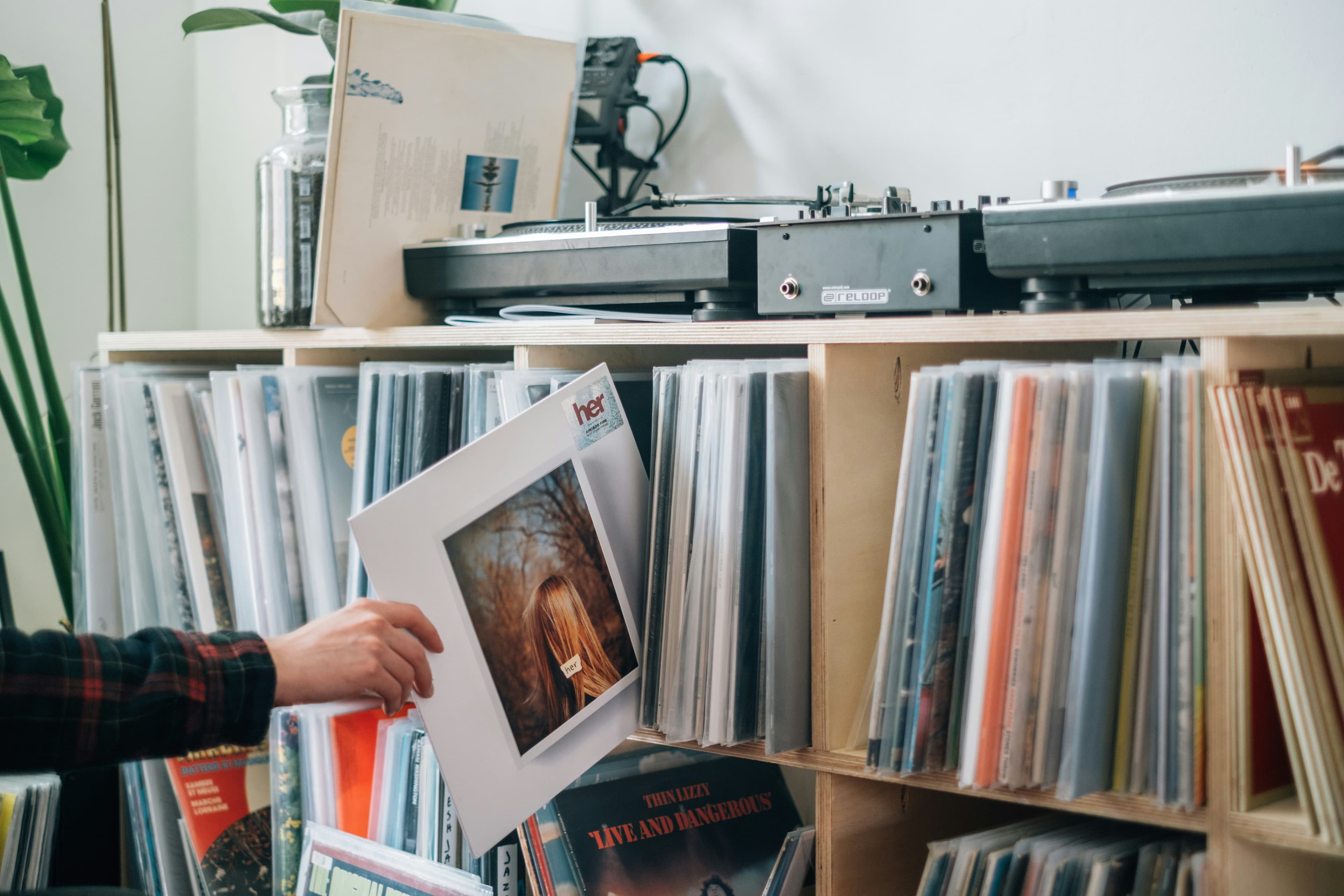 Eine Person nimmt eine Schallplatte aus einem Regal voller Schallplatten
