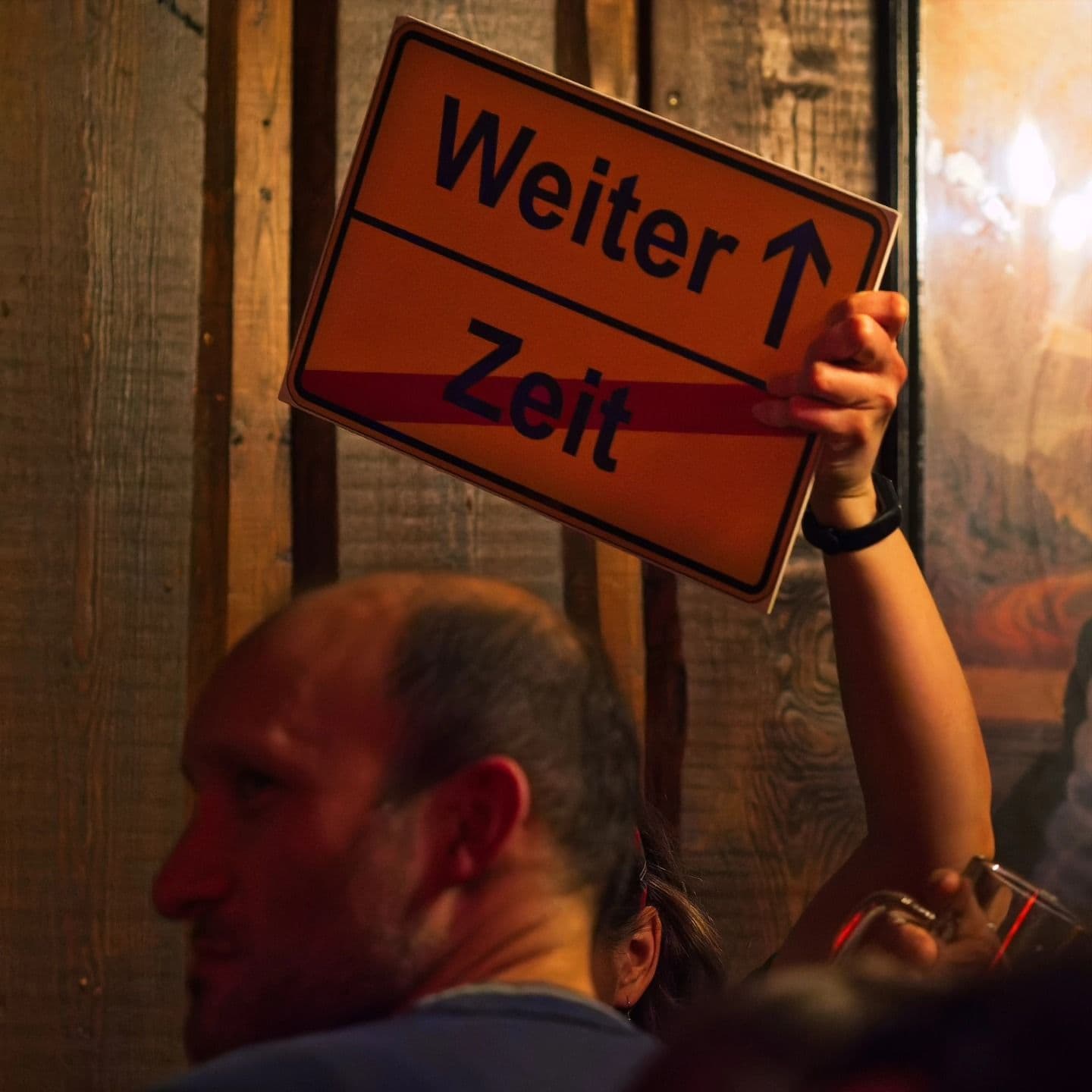 Eine Person hält ein Schild "Weiter, Zeit" in die Luft