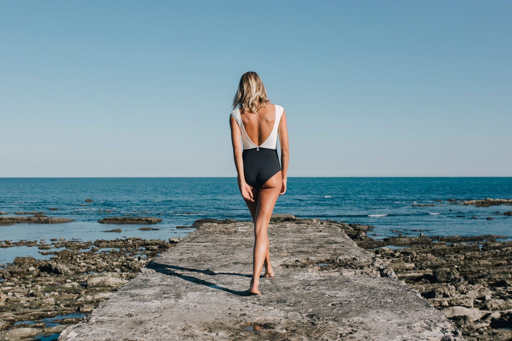 Eine Frau im Badeanzug von hinten fotografiert an einem Strand