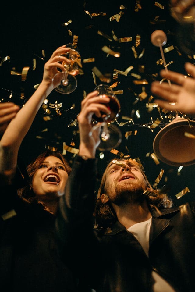 Menschen stehen im Glitzerregen und prosten sich zu
