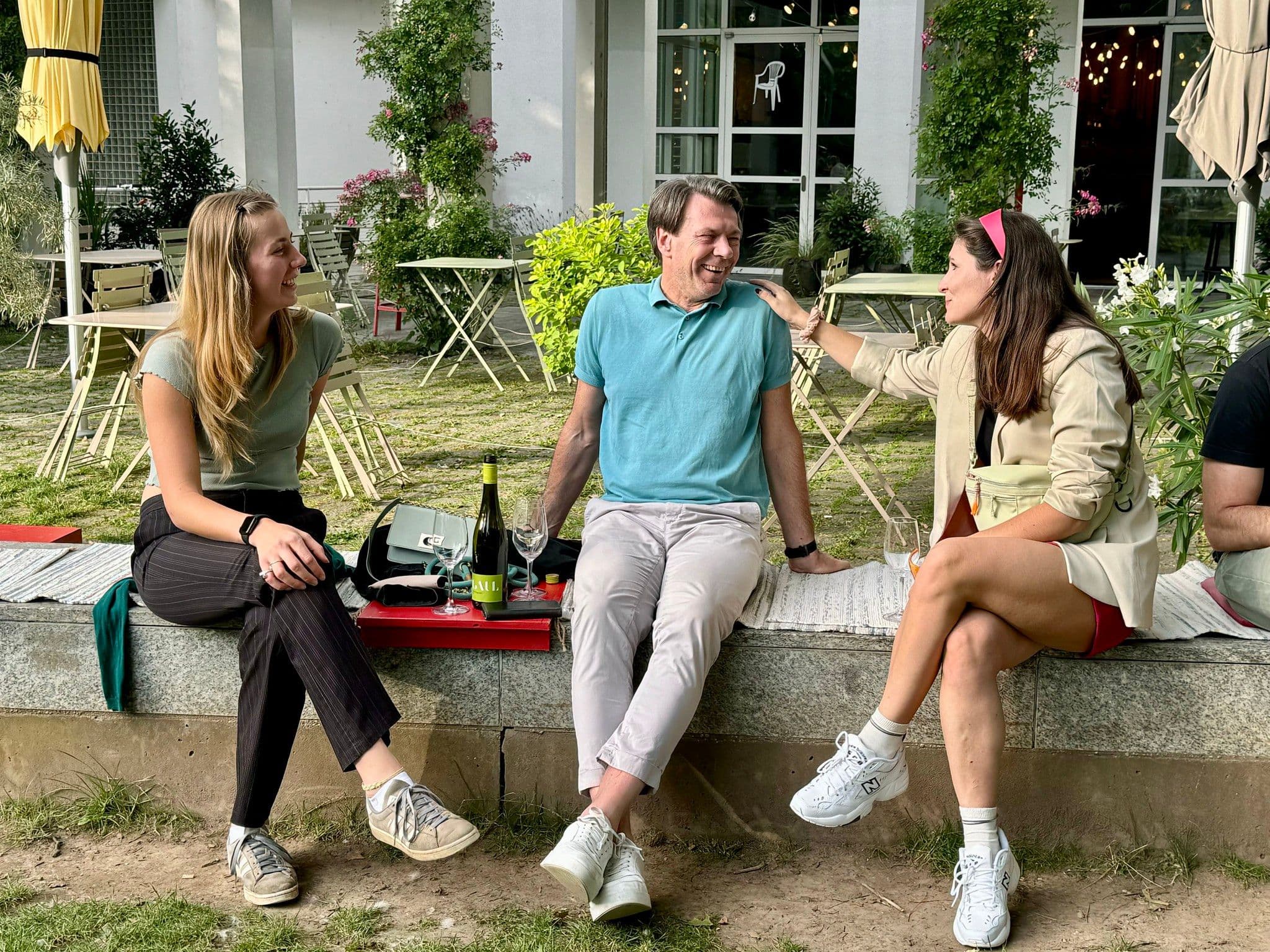 Menschen sitzen draußen und unterhalten sich, während sie Wein trinken.