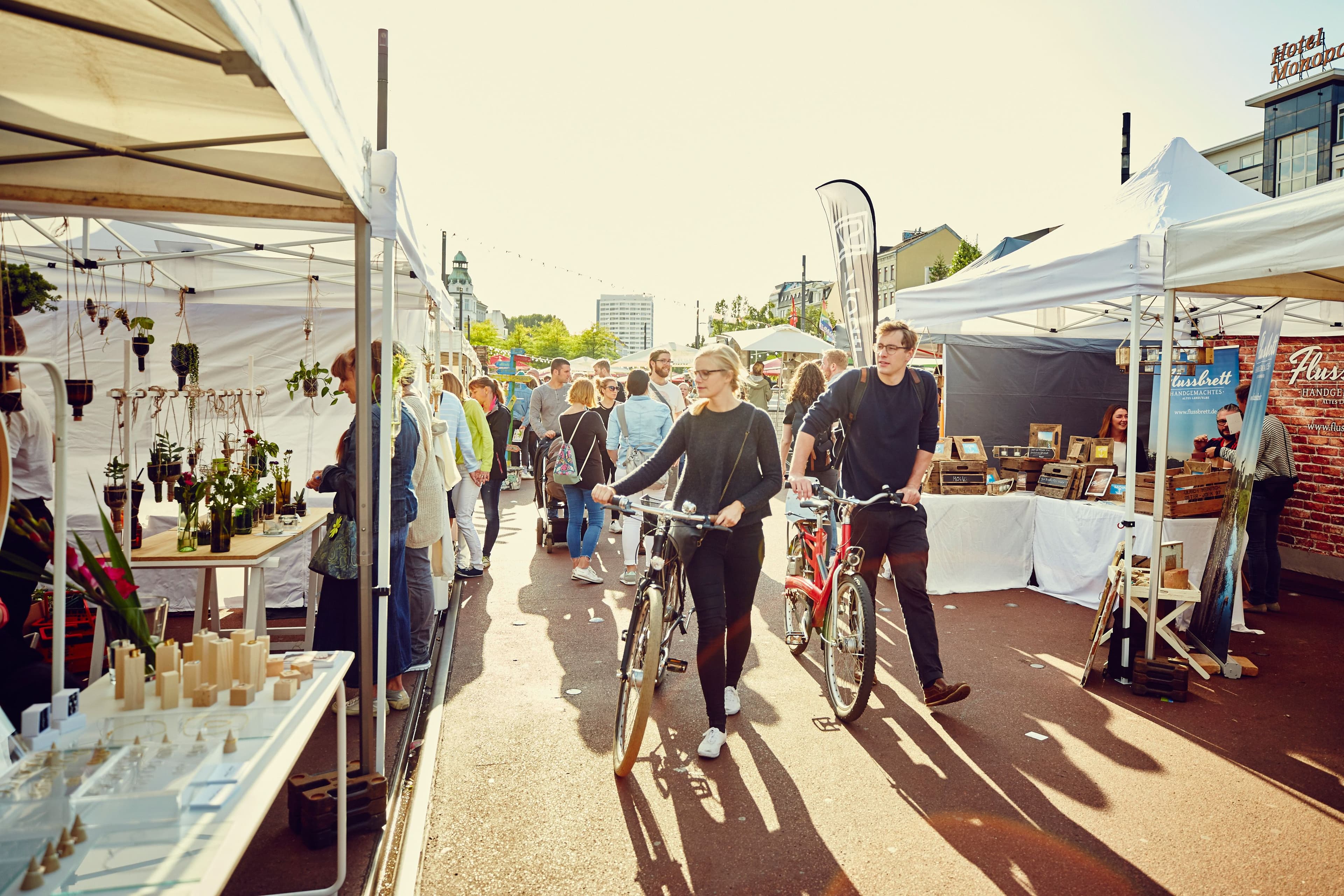 Personen laufen mit Fahrrädern über einen Markt