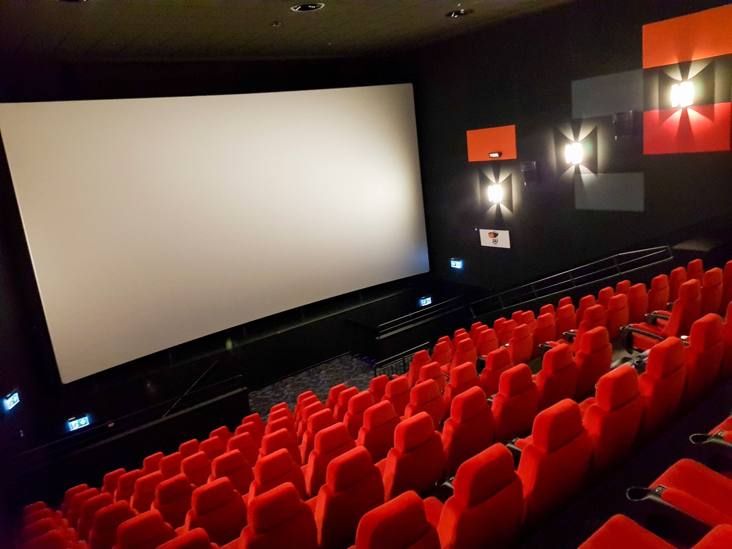 Leerer Kinosaal mit Leinwand und roten Kinosesseln