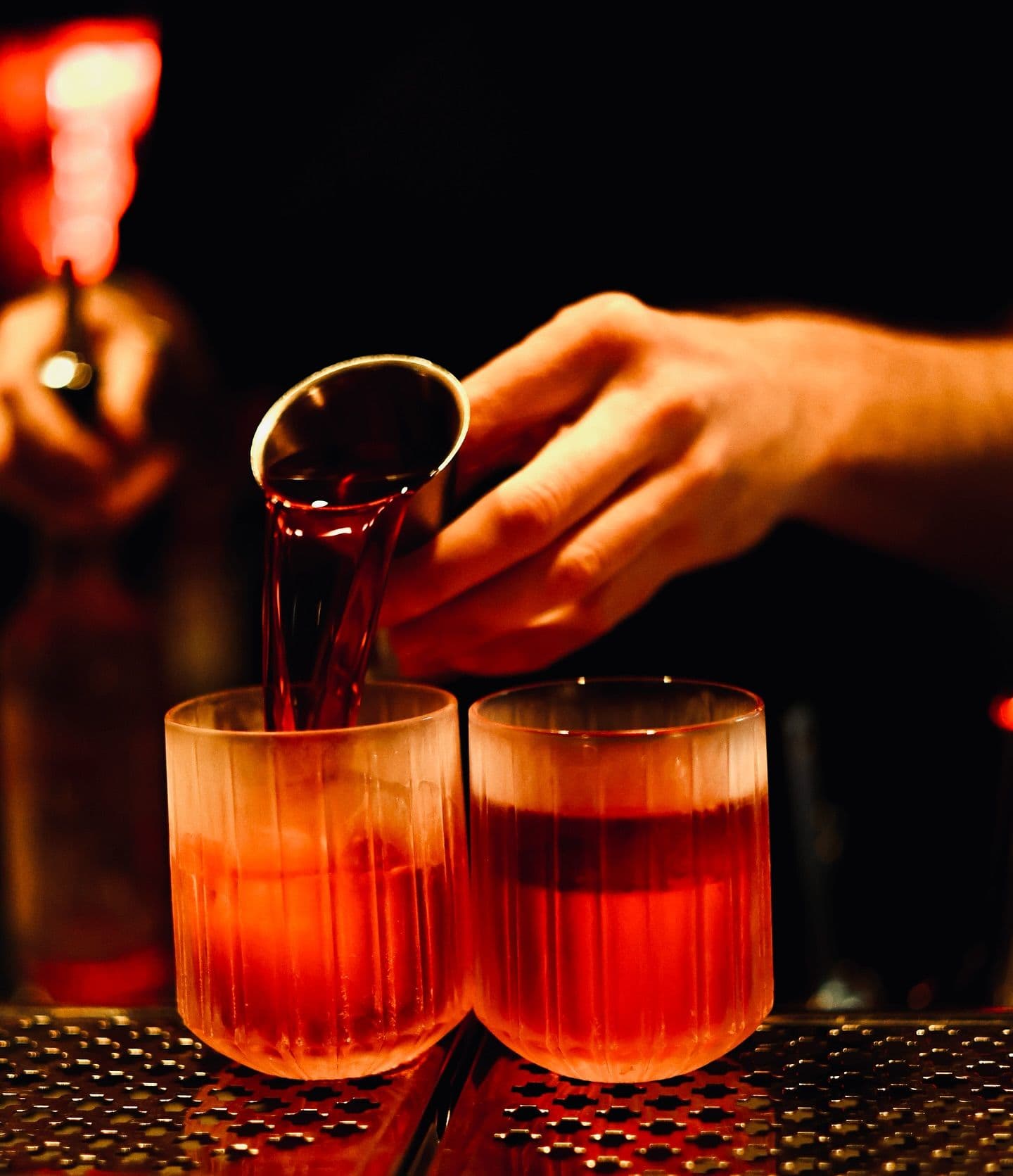 Nahaufnahme von zwei Gläsern, die mit einem Drink befüllt werden