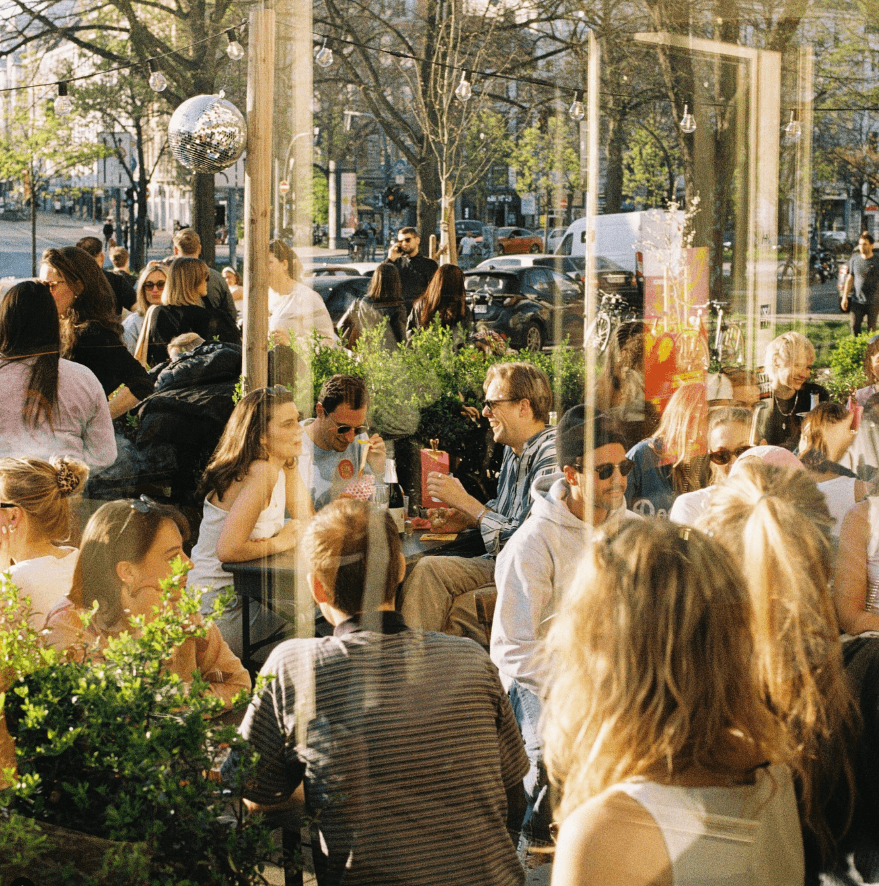 Menschen stehen und sitzen auf einer Terrasse und trinken und unterhalten sich