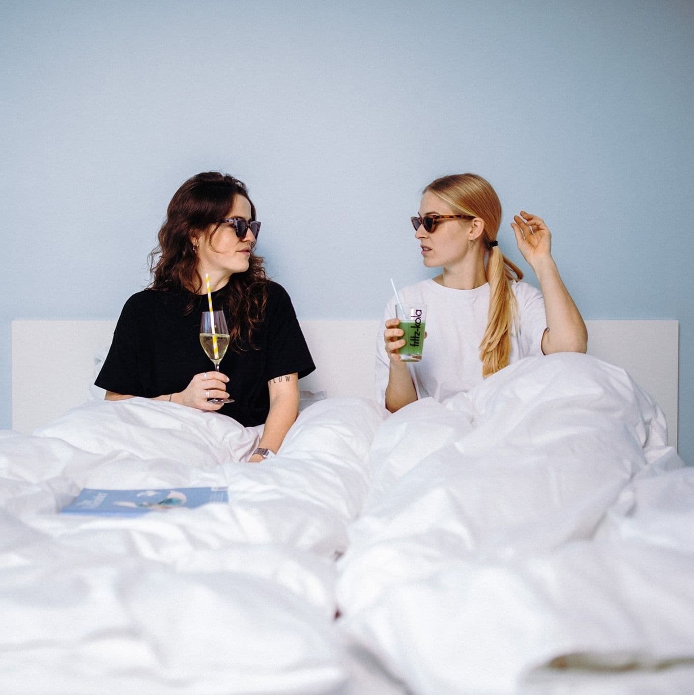 Zwei Personen mit Gläsern im Bett