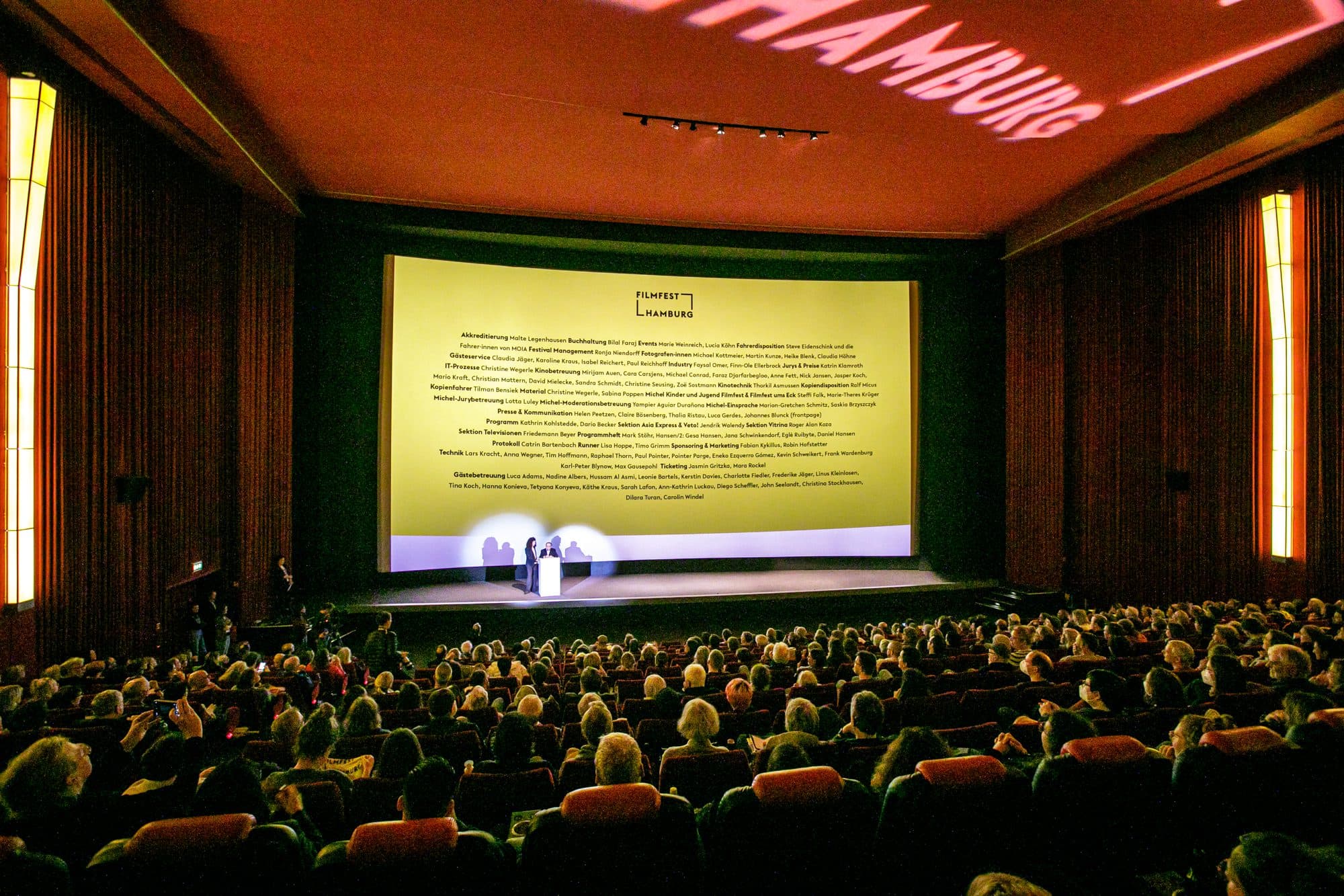 Personen sitzen in einem Kinosaal und schauen auf die Leinwand.
