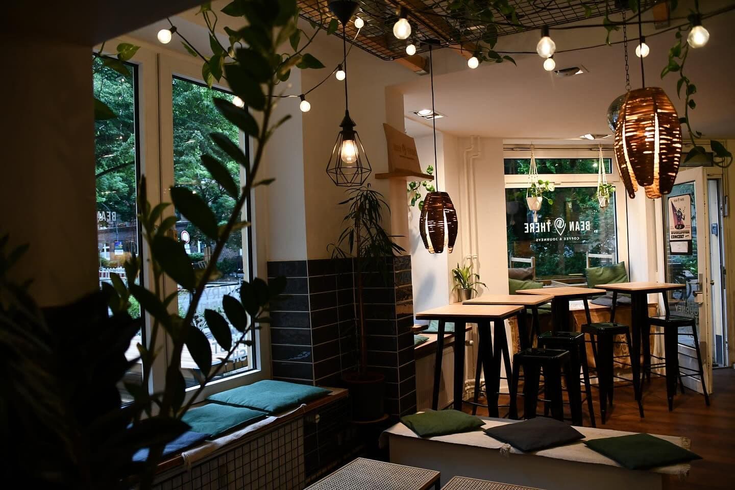 Innenansicht des Bean There Cafés mit Tischen, Stühlen und Pflanzen