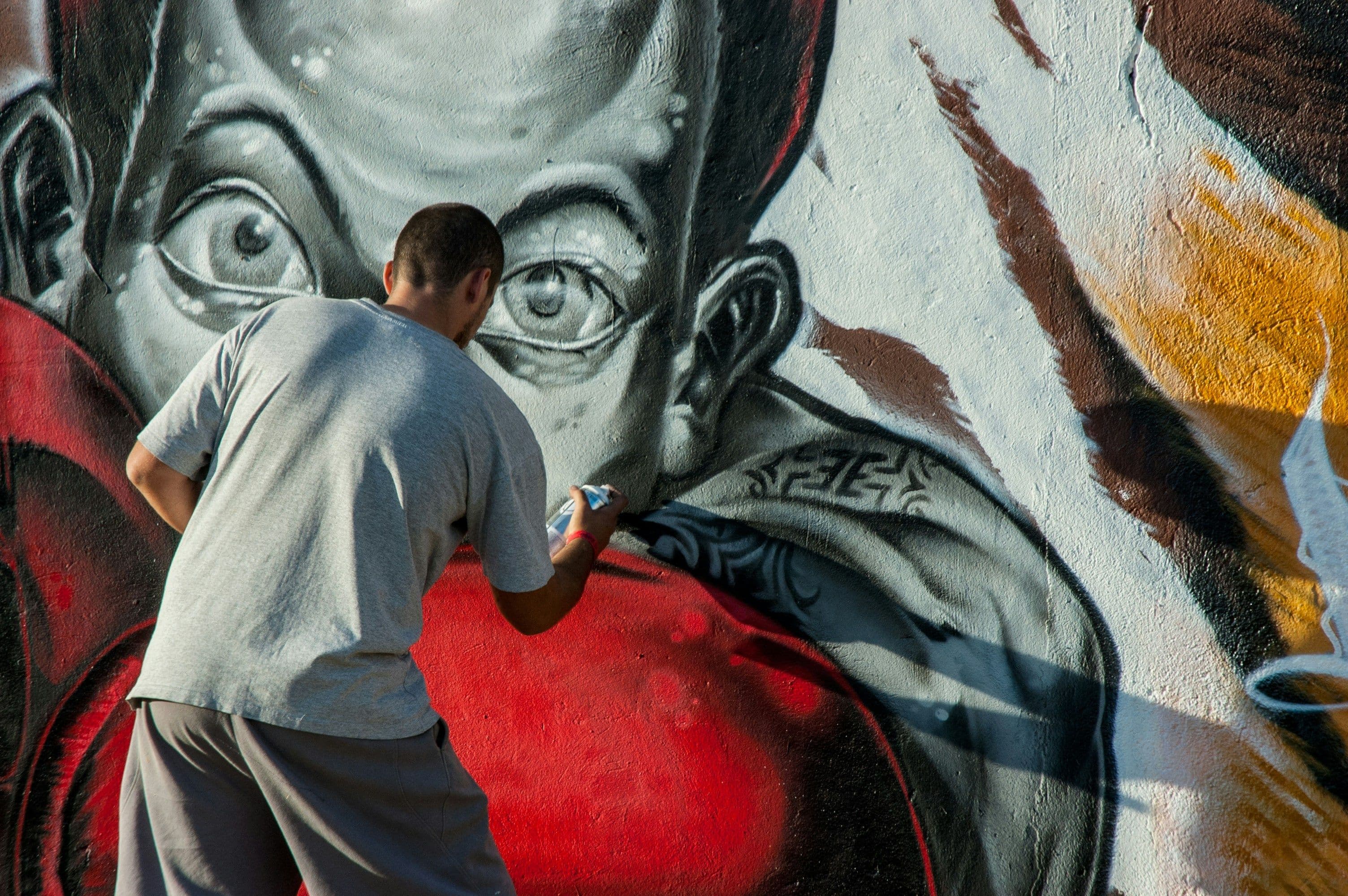 Ein Mann sprayt einen Menschen an eine Wand