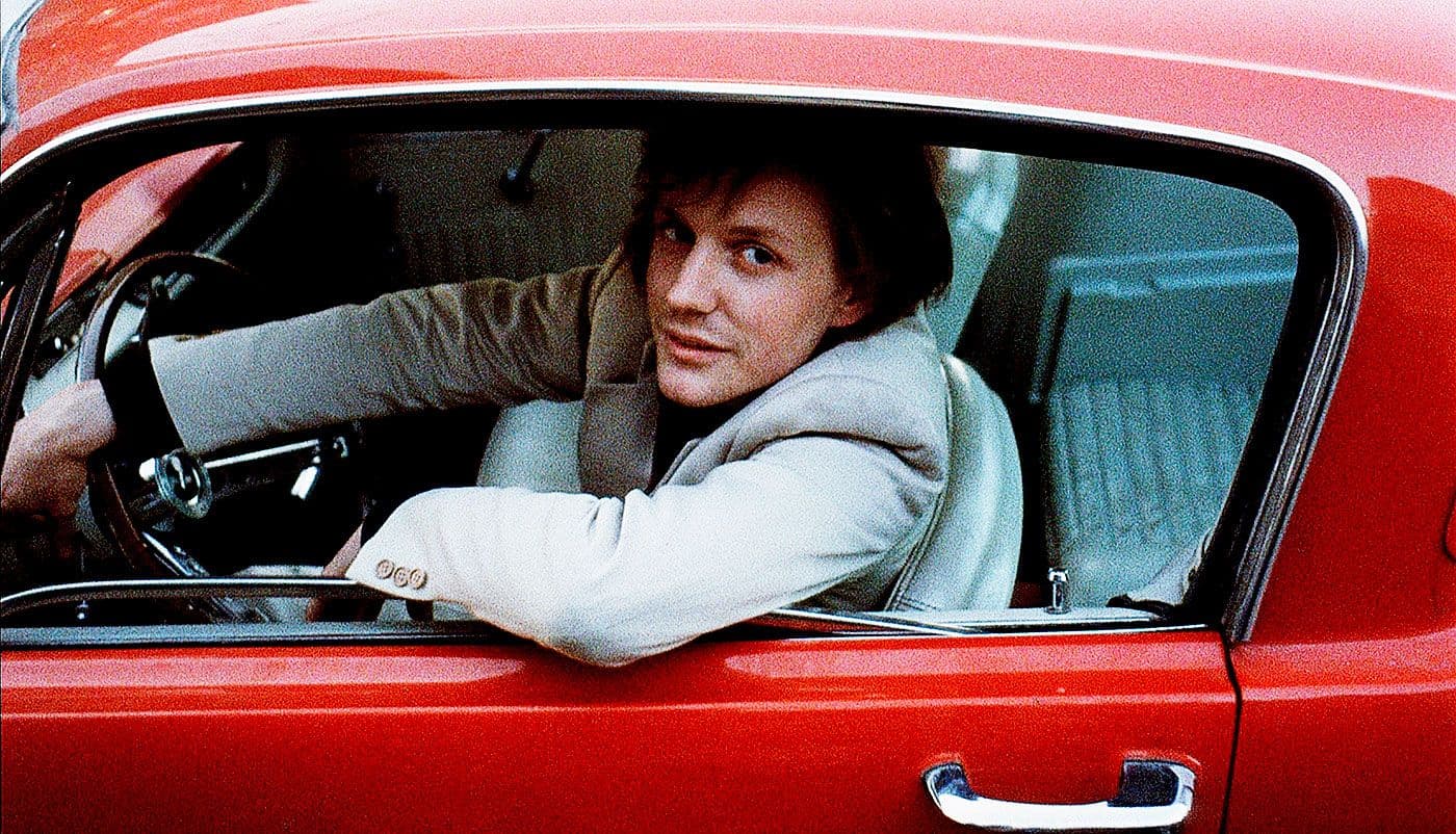 Ein Mann lehnt sich lässig aus dem Fenster eines roten Autos