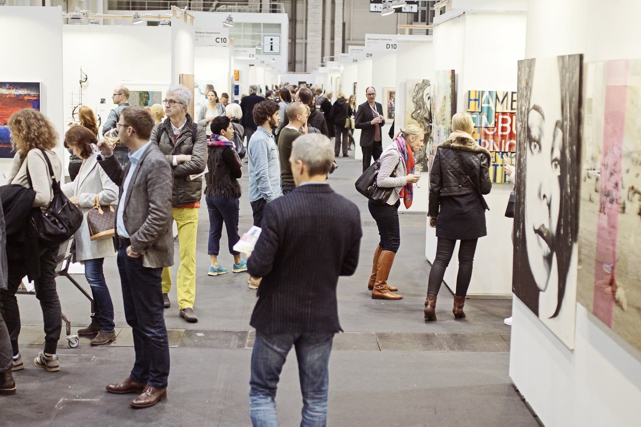Menschen sehen sich Kunst in den Messehallen an.
