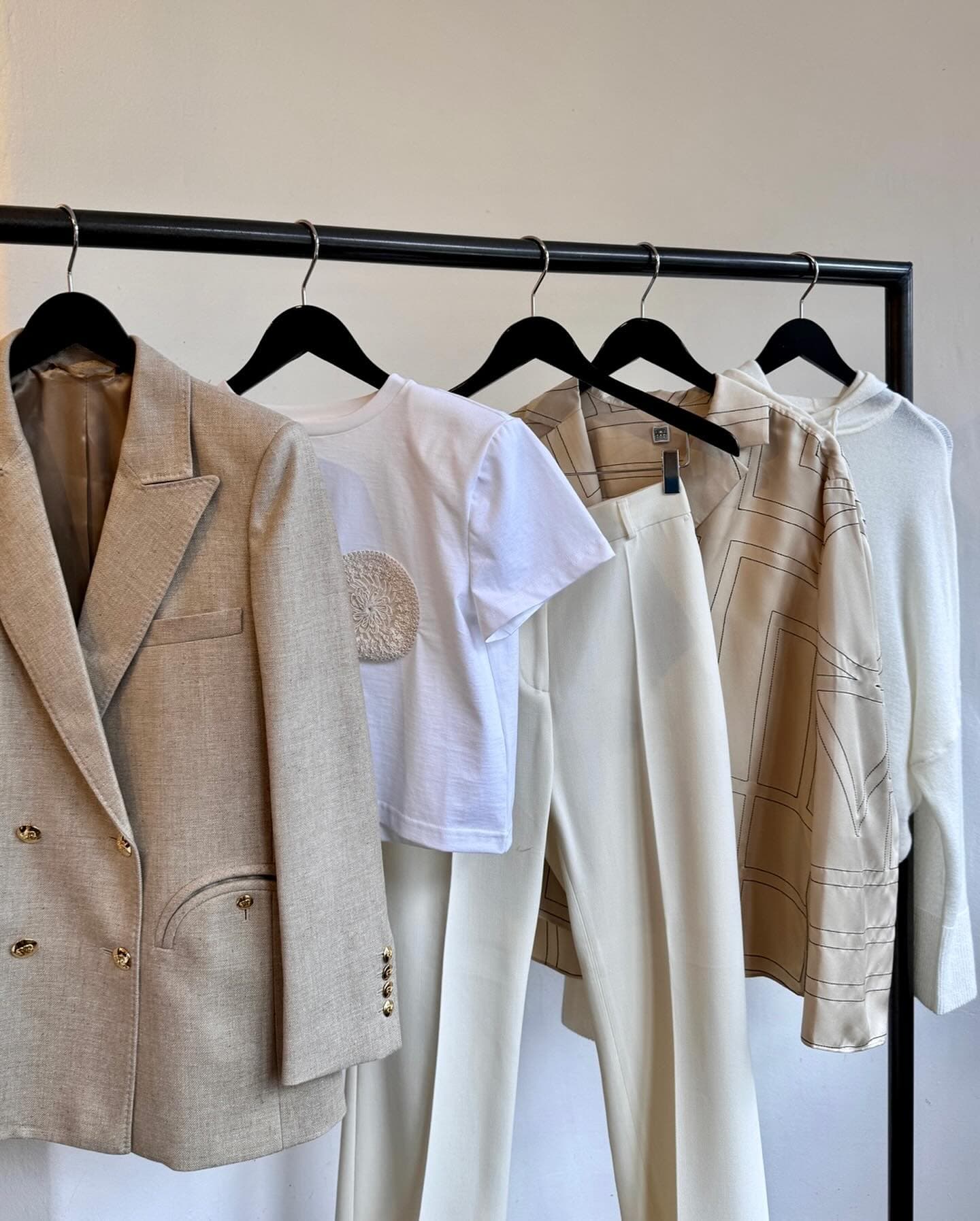 Kleiderstange, auf der mehrere weiße und beige Kleidungsstücke von Anita Hass hängen