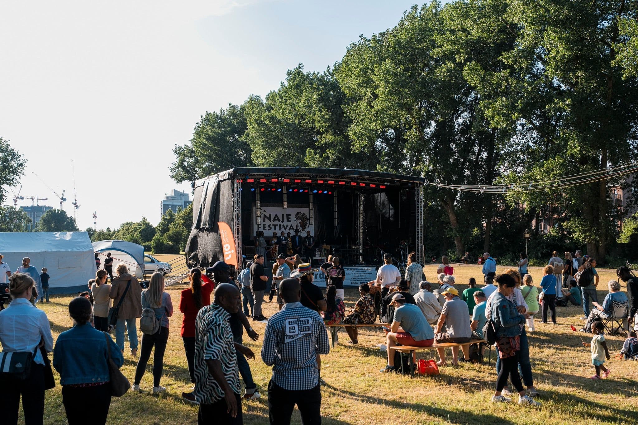 Personen stehen auf dem Rasen vor einer Bühne