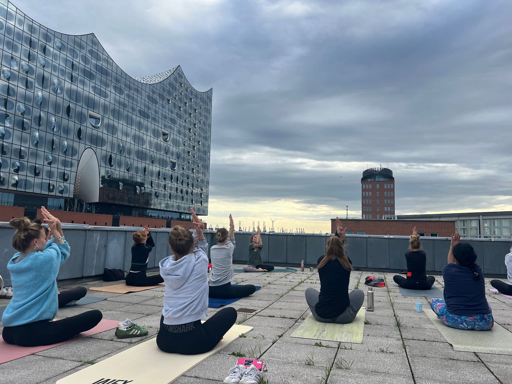 Menschen praktizieren Yoga mit Blick auf die Elbphilharmonie