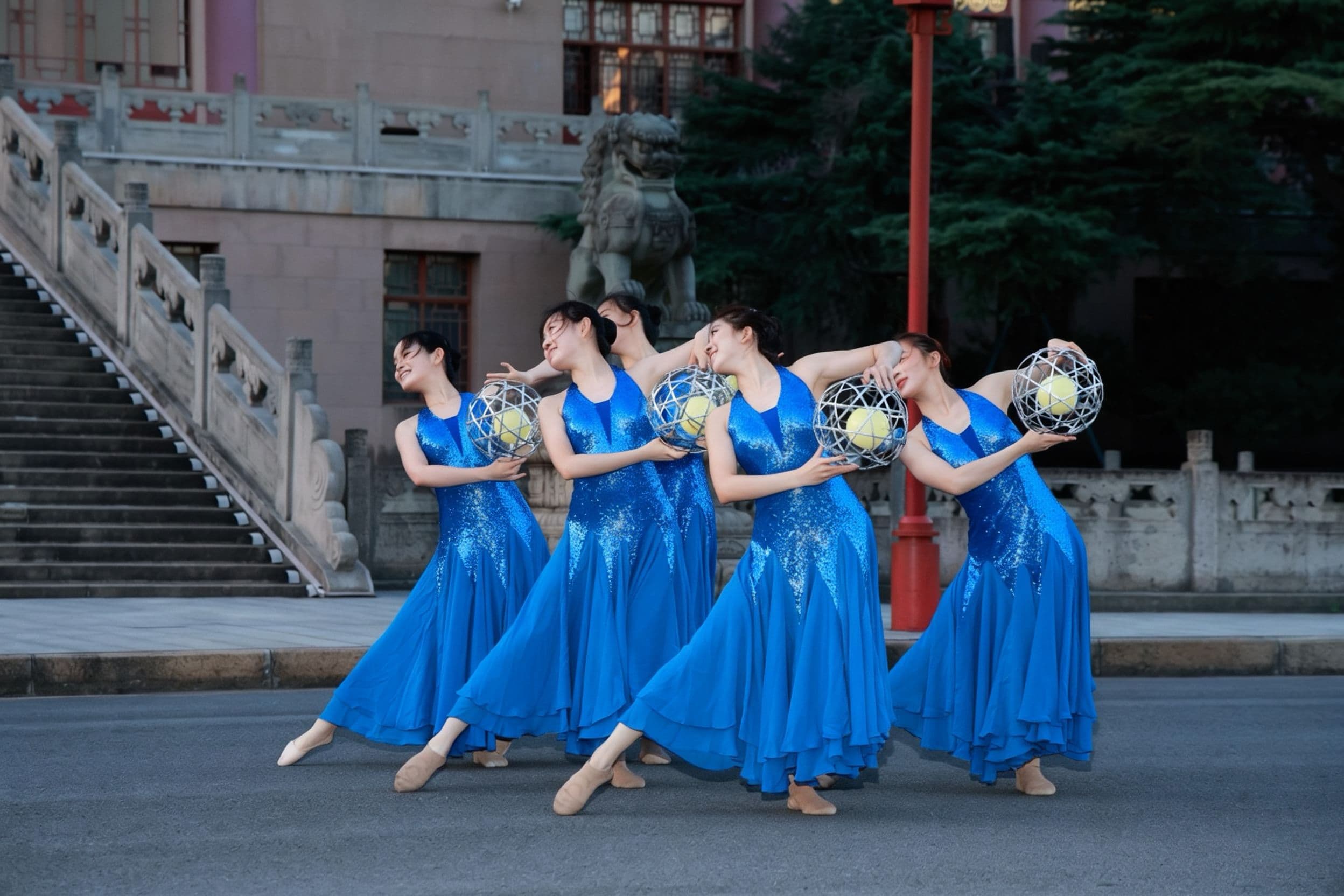 Eine Gruppe Frauen in blauen Kleidern tanzt auf einem Platz