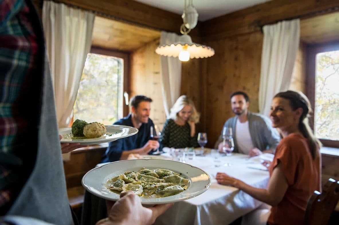 Eine Person serviert Schlutzkrapfen in einer urige aussehenden Hütte