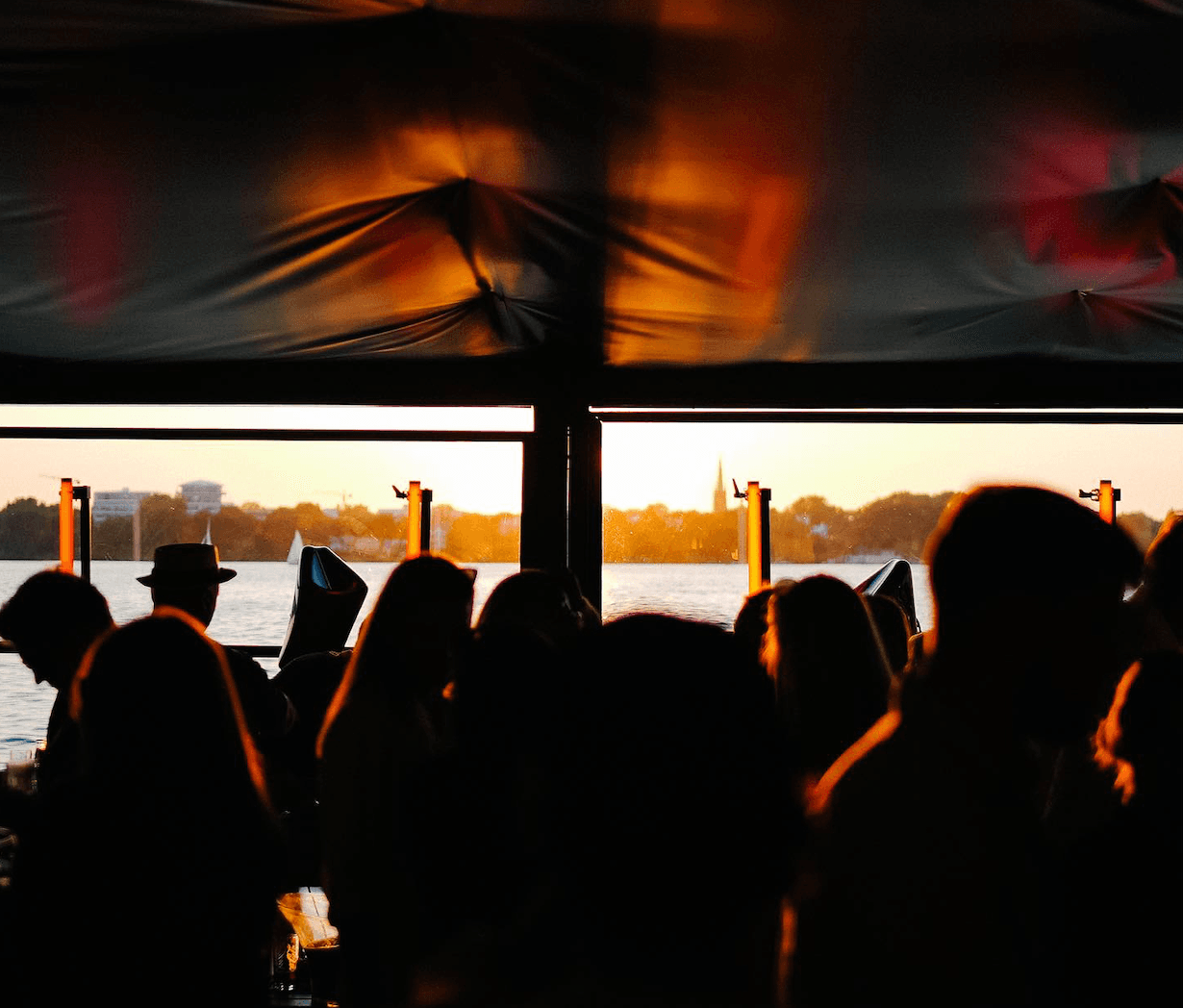 Menschen tanzen im Seehaus bei Sonnenuntergang
