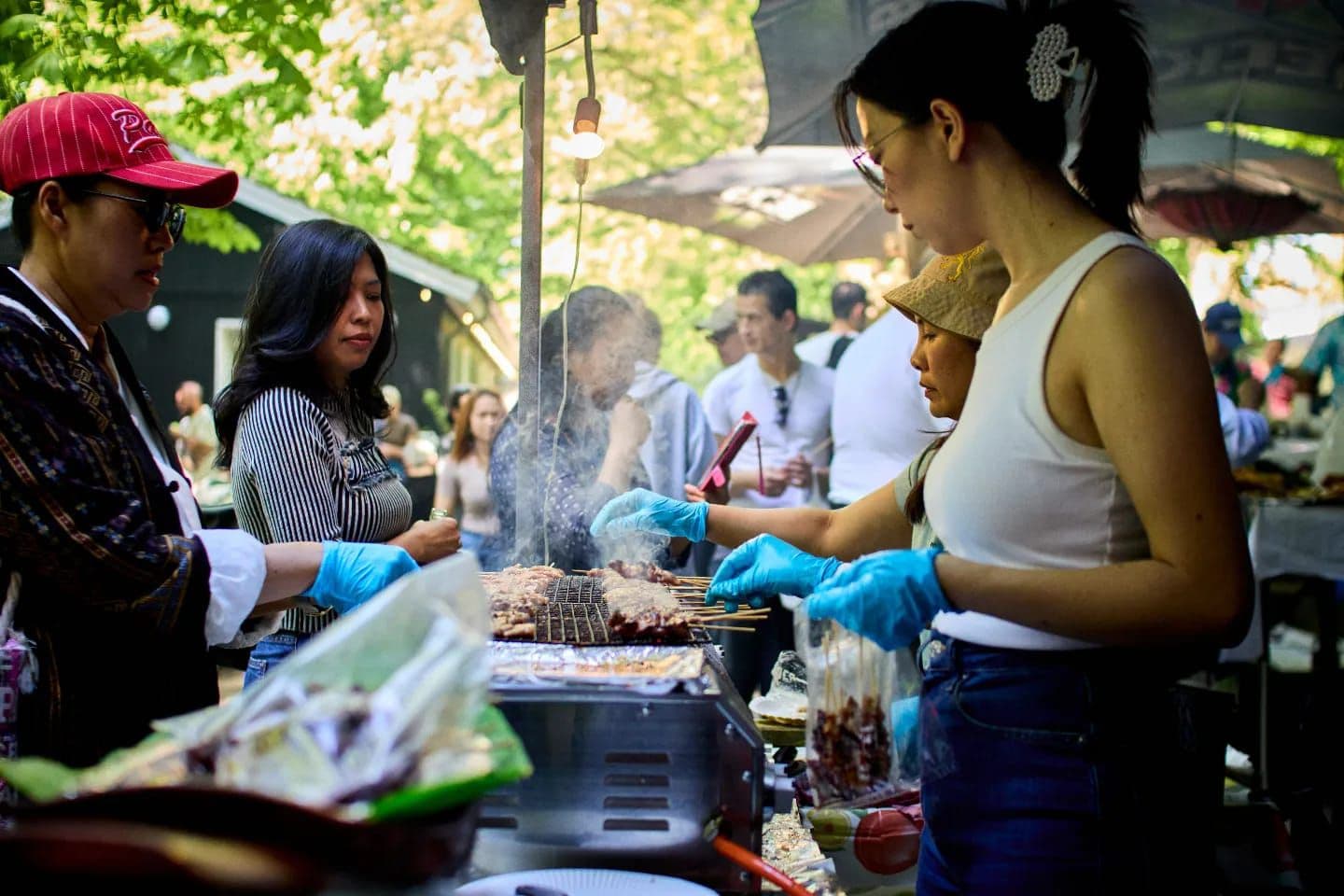 Personen an einem Grill beim Thai Food Markt