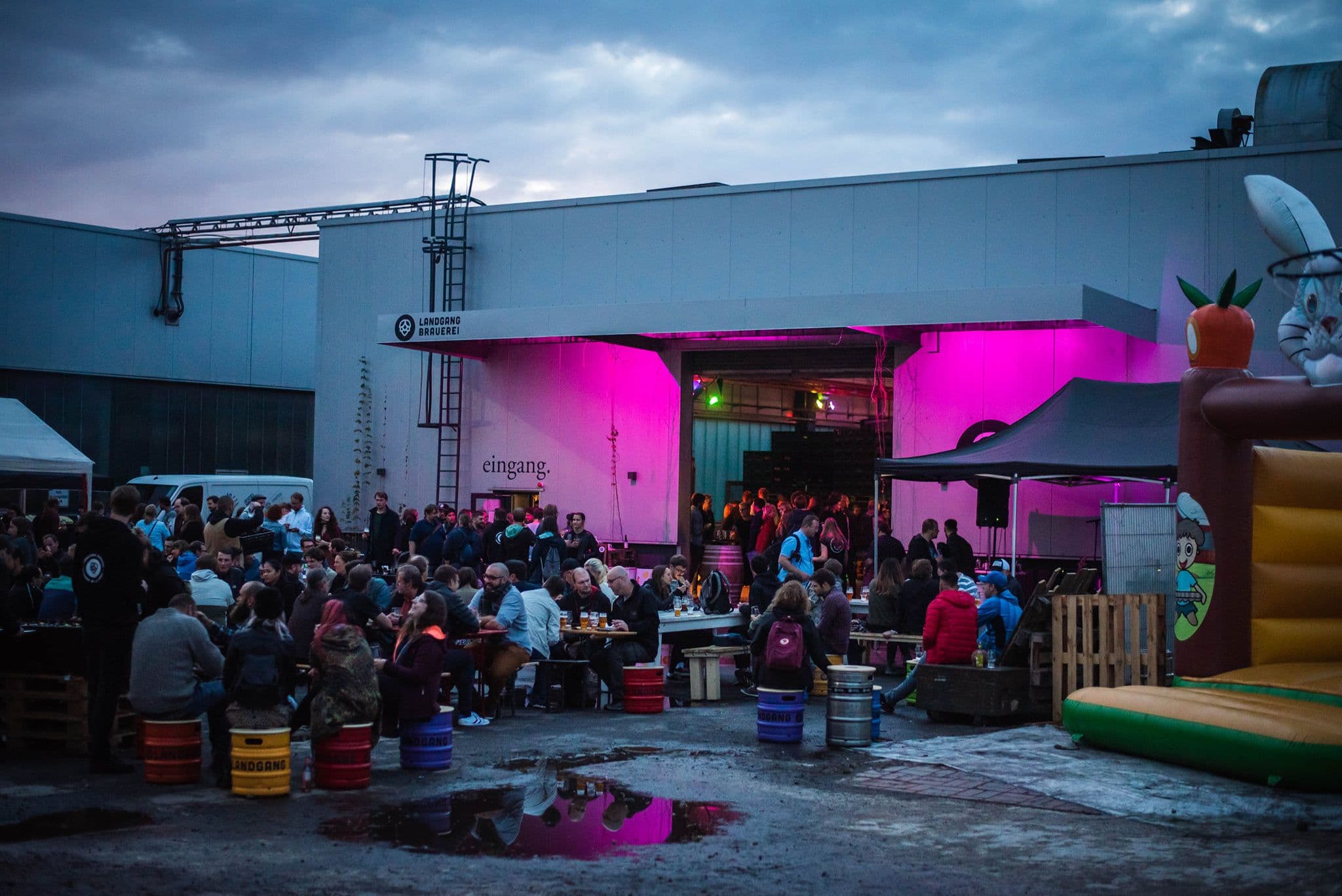 Menschen stehen und sitzen vor der Landgang Brauerei an Tischen und trinken und unterhalten sich