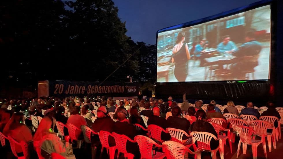 Personen beim Open-Air-Schanzen Kino auf Plastikstühlen