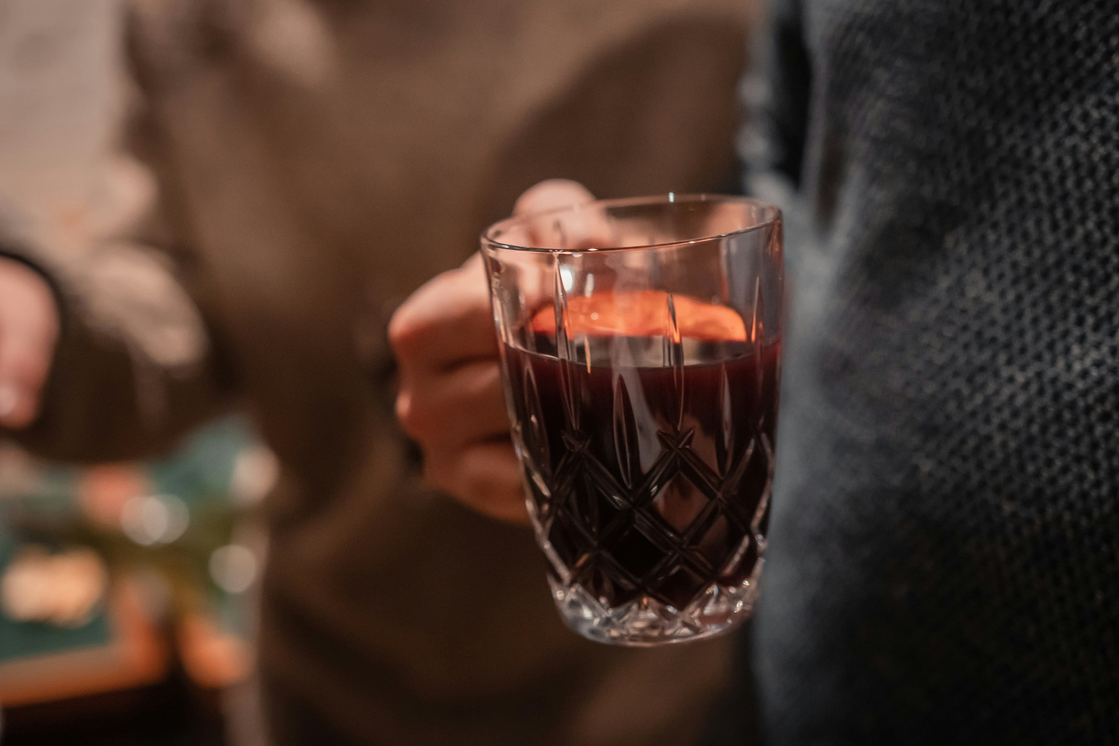Eine Person hält eine Glastasse mit Glühwein in der Hand