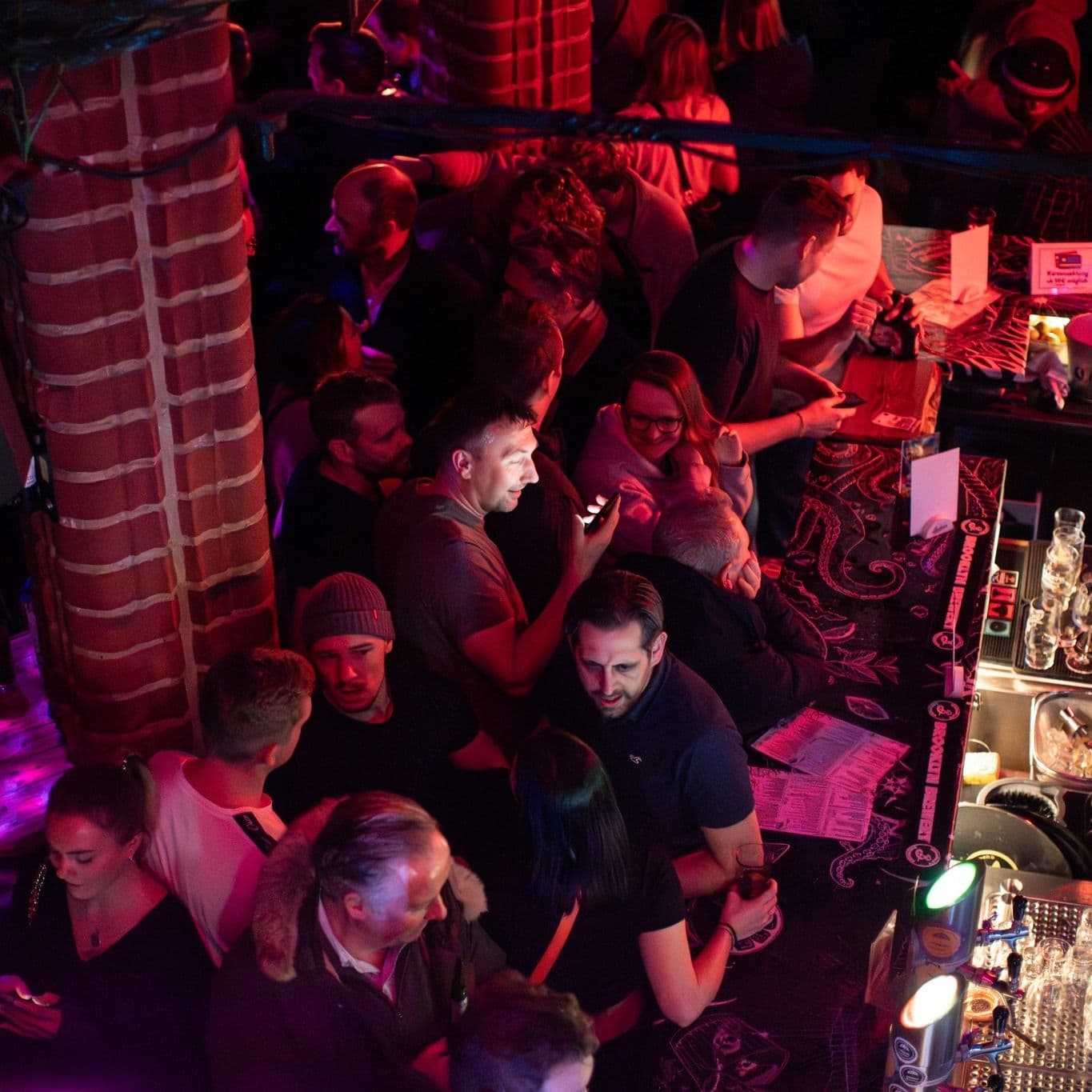 Bar mit Besucher:innen und gedämmtem Licht im Freundlich + Kompetent