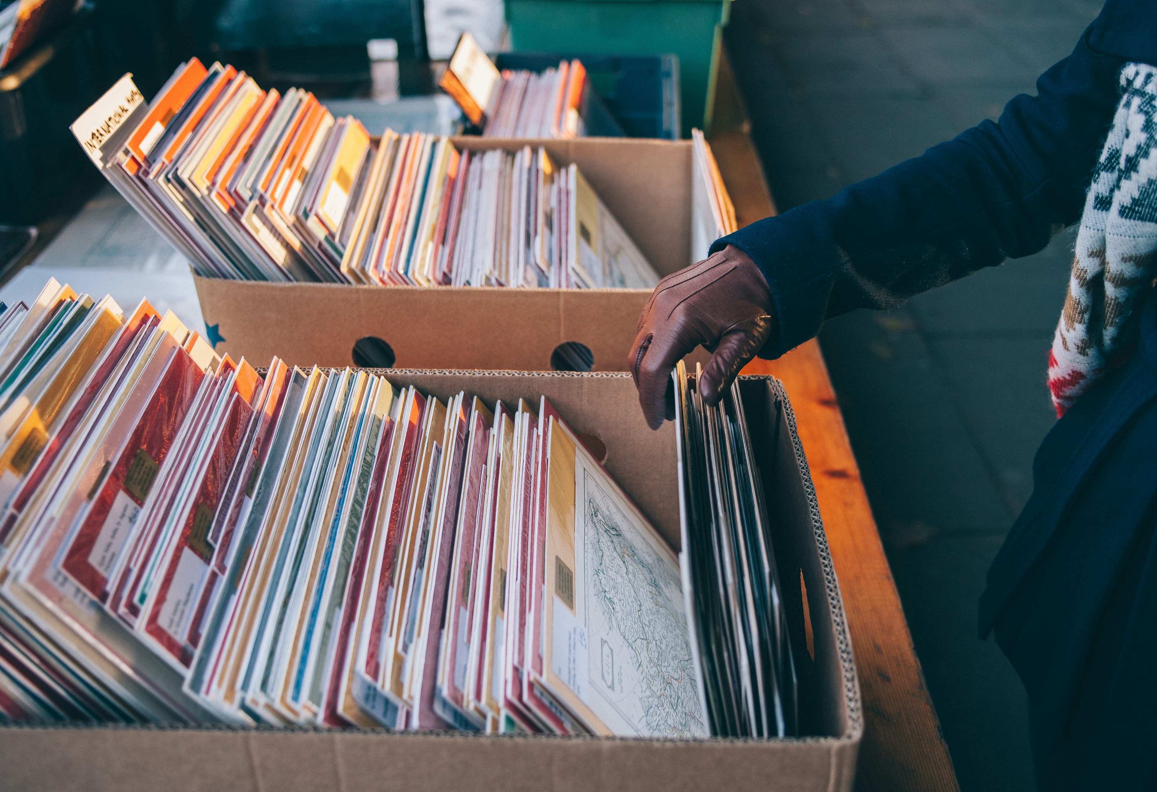Eine Person sieht eine Kiste mit Schallplatten durch.