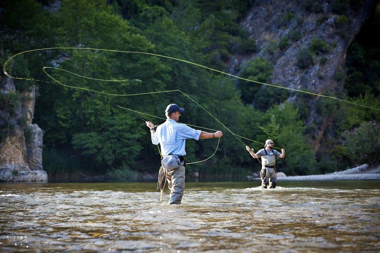 Zwei Fliegenfischer stehen im Wasser und werfen eine Angel aus