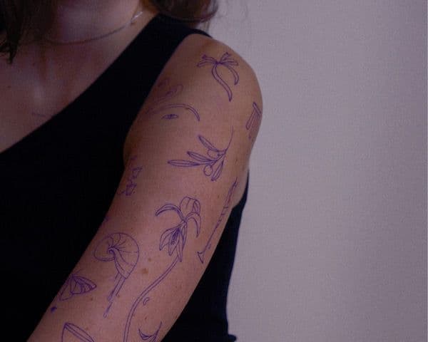 Oberarm, auf dem viele kleinere Tattoomotive aufgezeichnet sind
