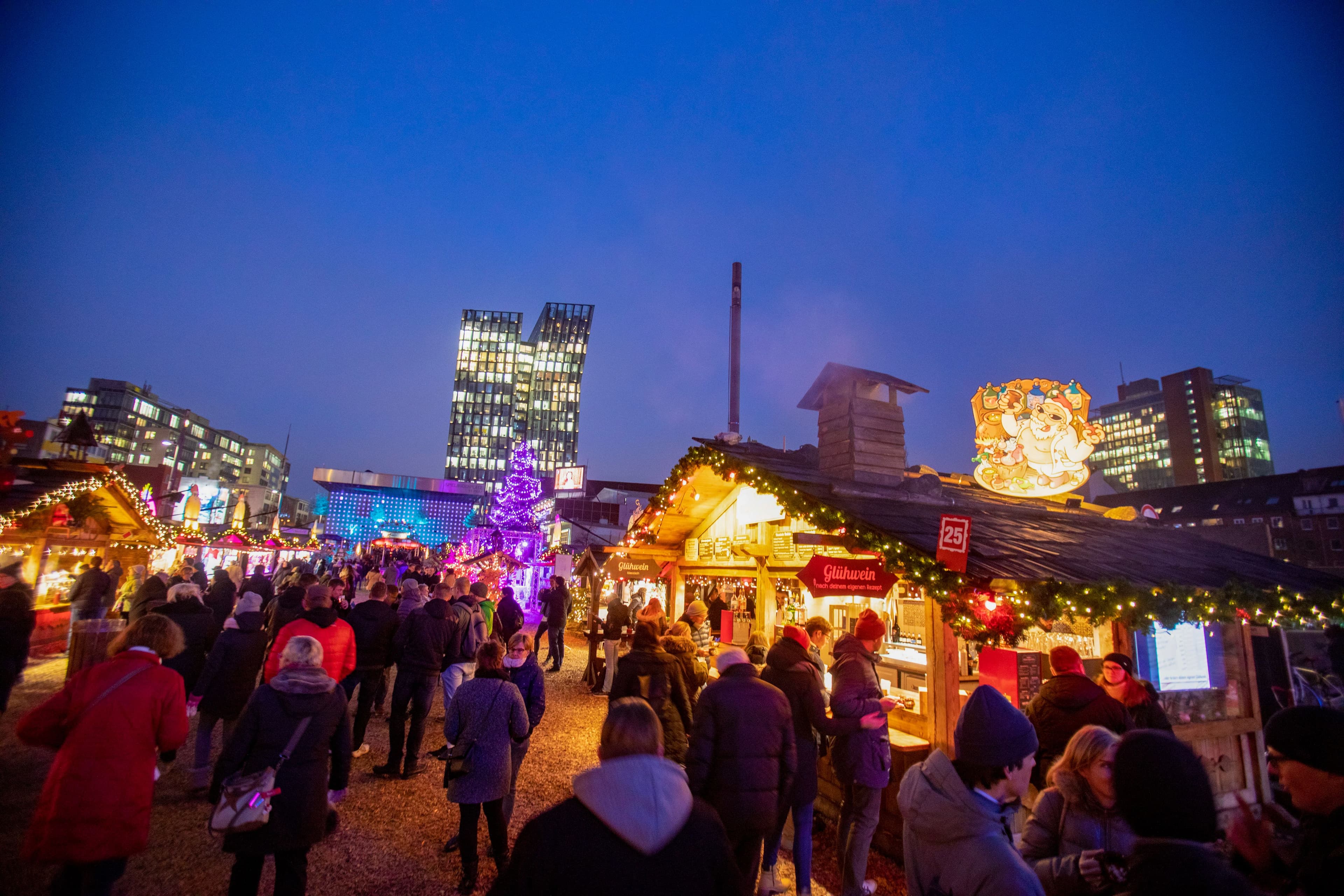 Menschen laufen über den erleuchteten Weihnachtsmarkt am Spielbudenplatz