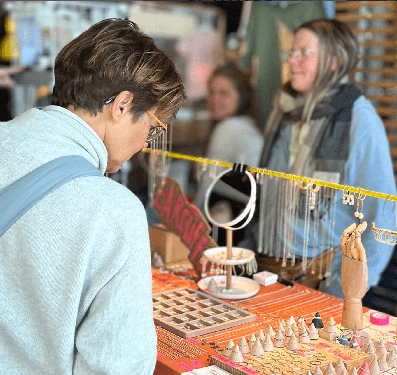 Eine Frau schaut sich Schmuck an einem Marktstand an