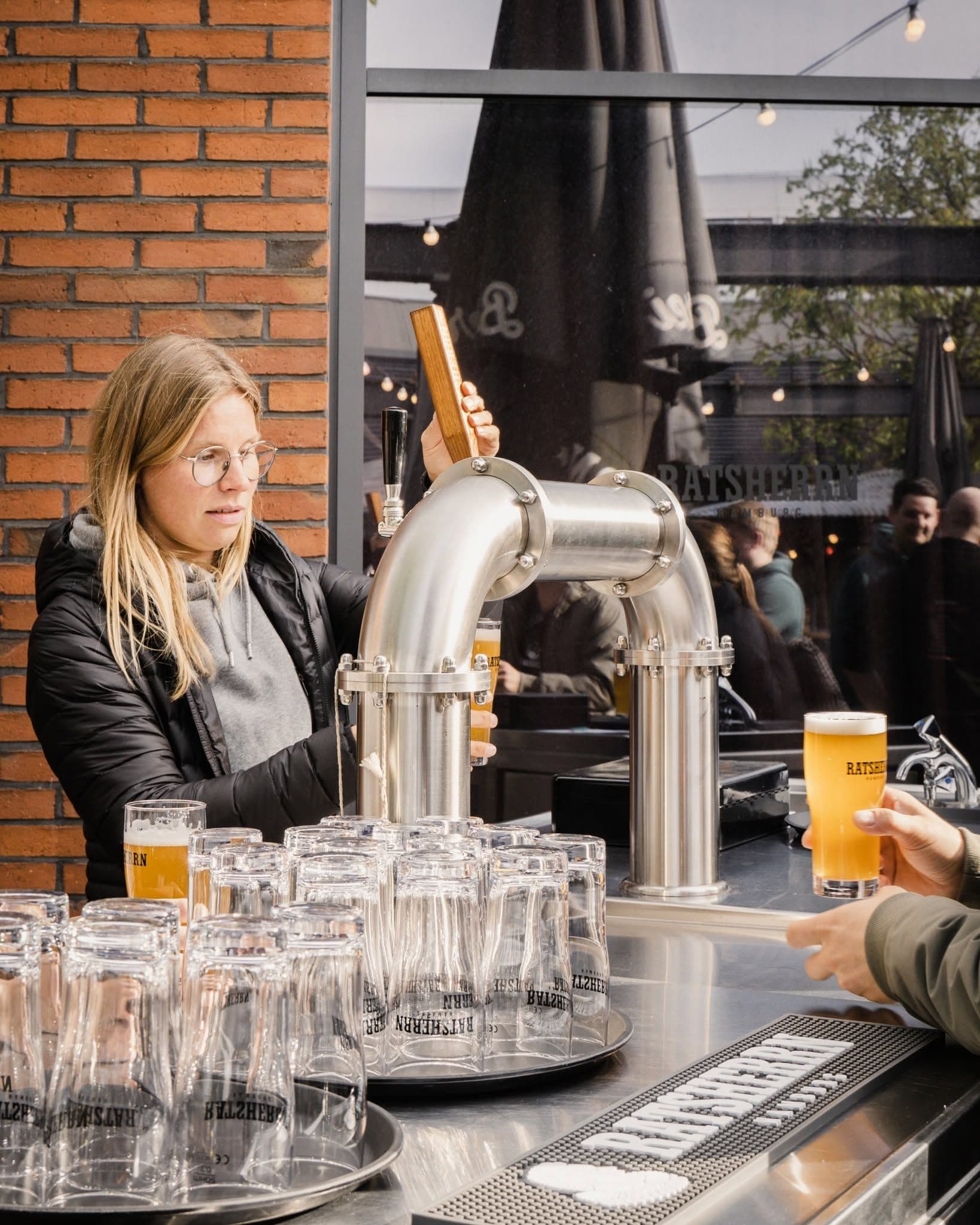 Eine Frau zapft sich ein Bier von Ratsherrn