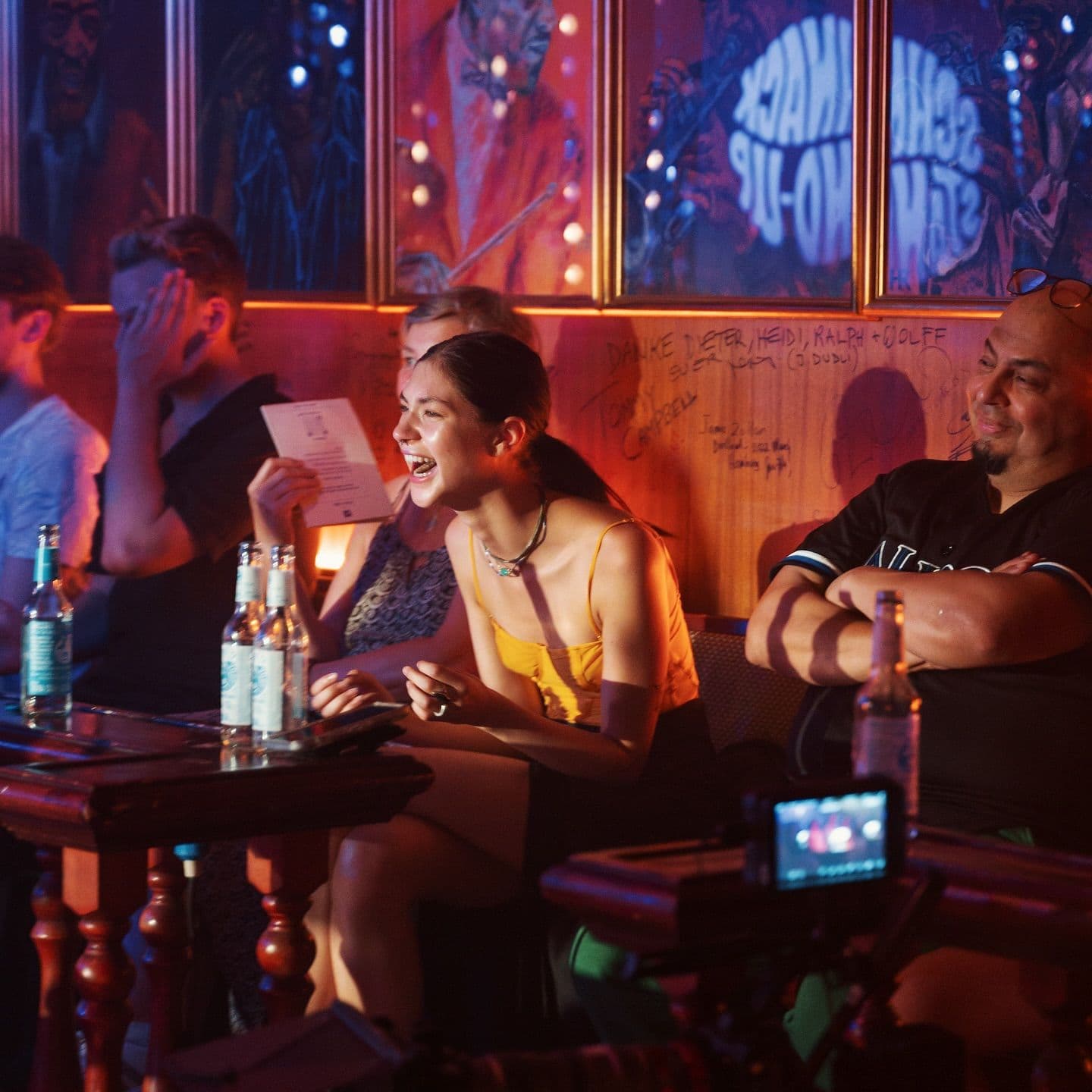 Menschen lachen in einer Bar, während sie sich eine Stand-Up Show anschauen.